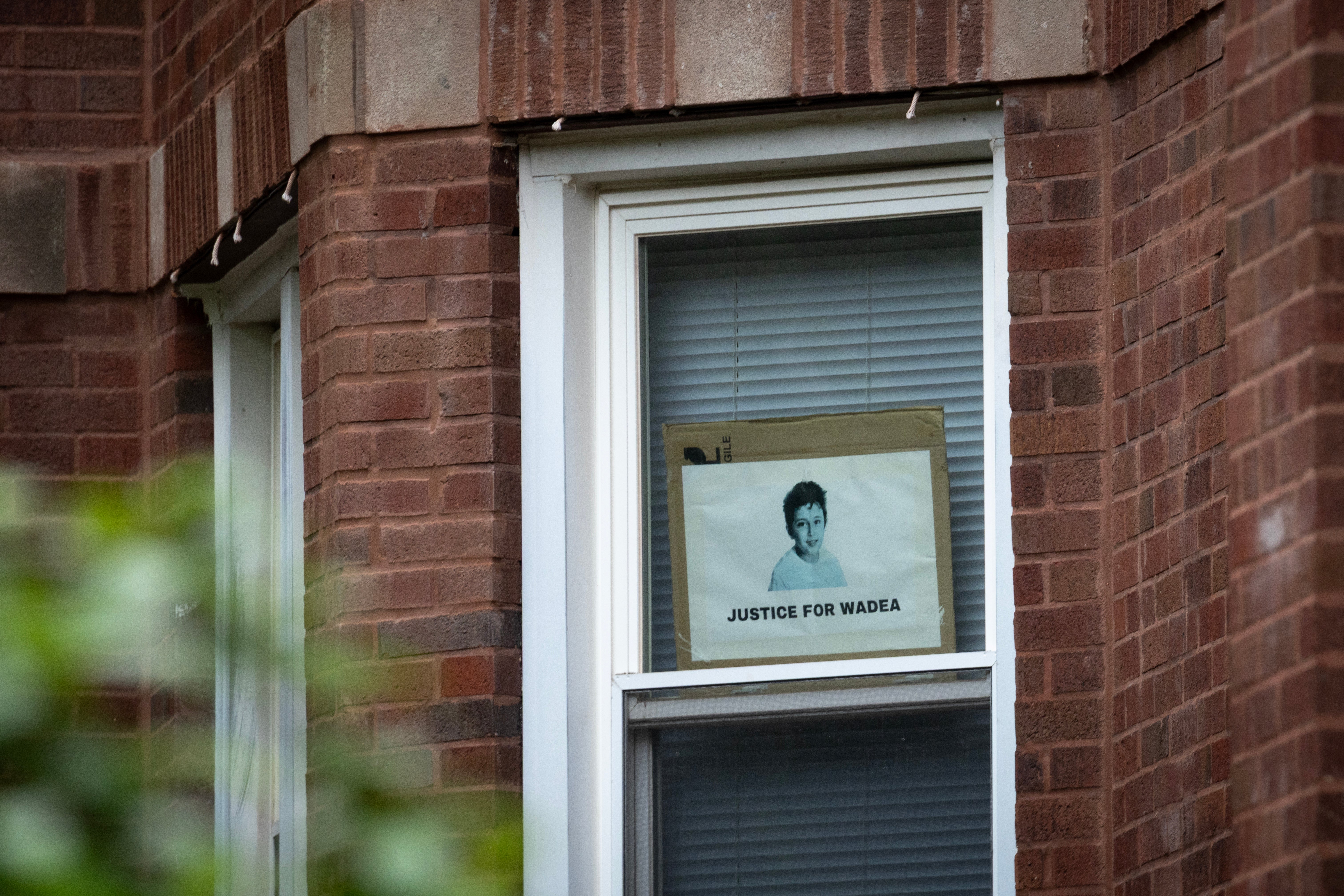 A sign calling for justice for Wadea hangs in the window of an apartment reported to belong to shooting suspect Elias Rodriguez.