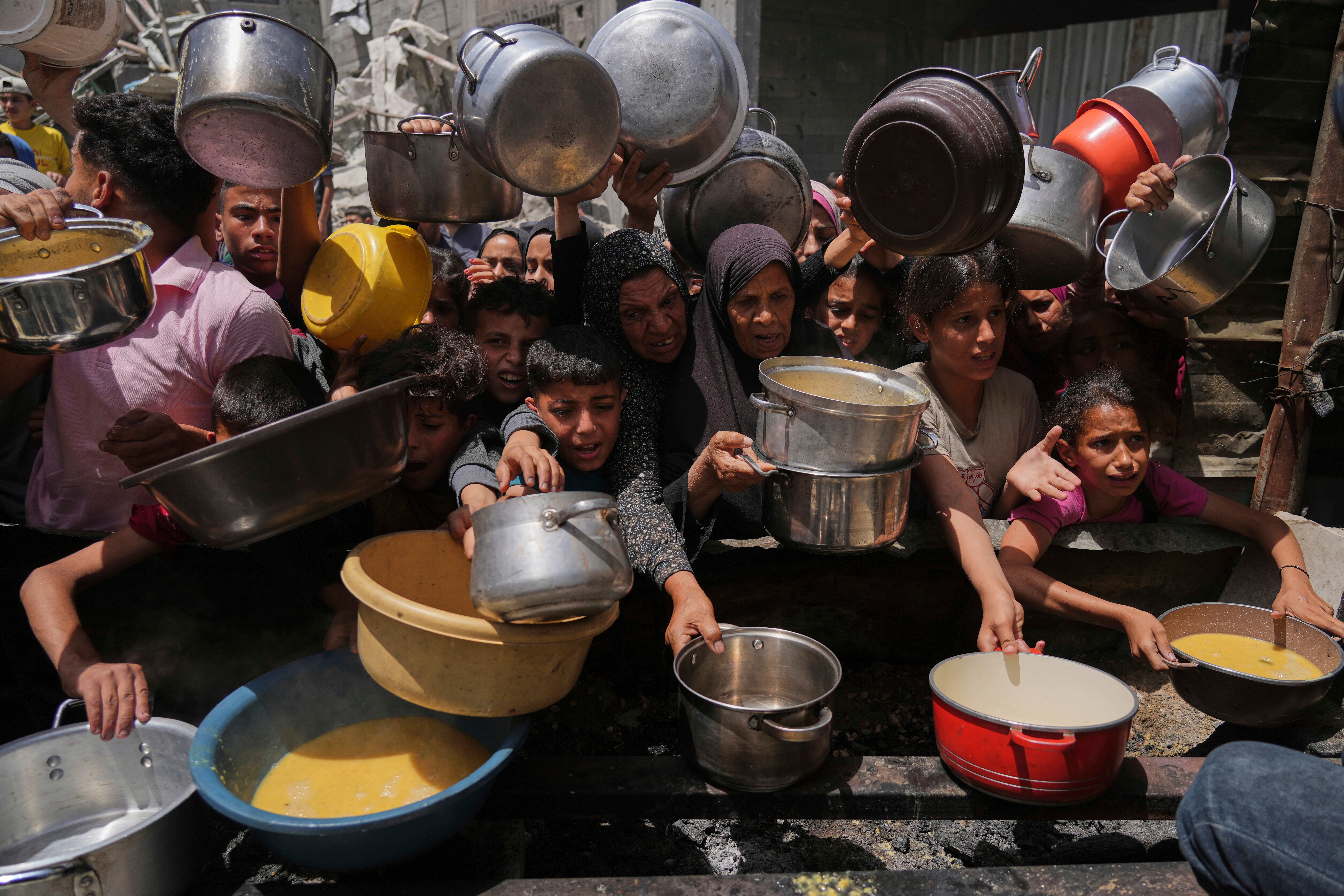 Palestinians struggle to get donated food at a community kitchen in Jabalia