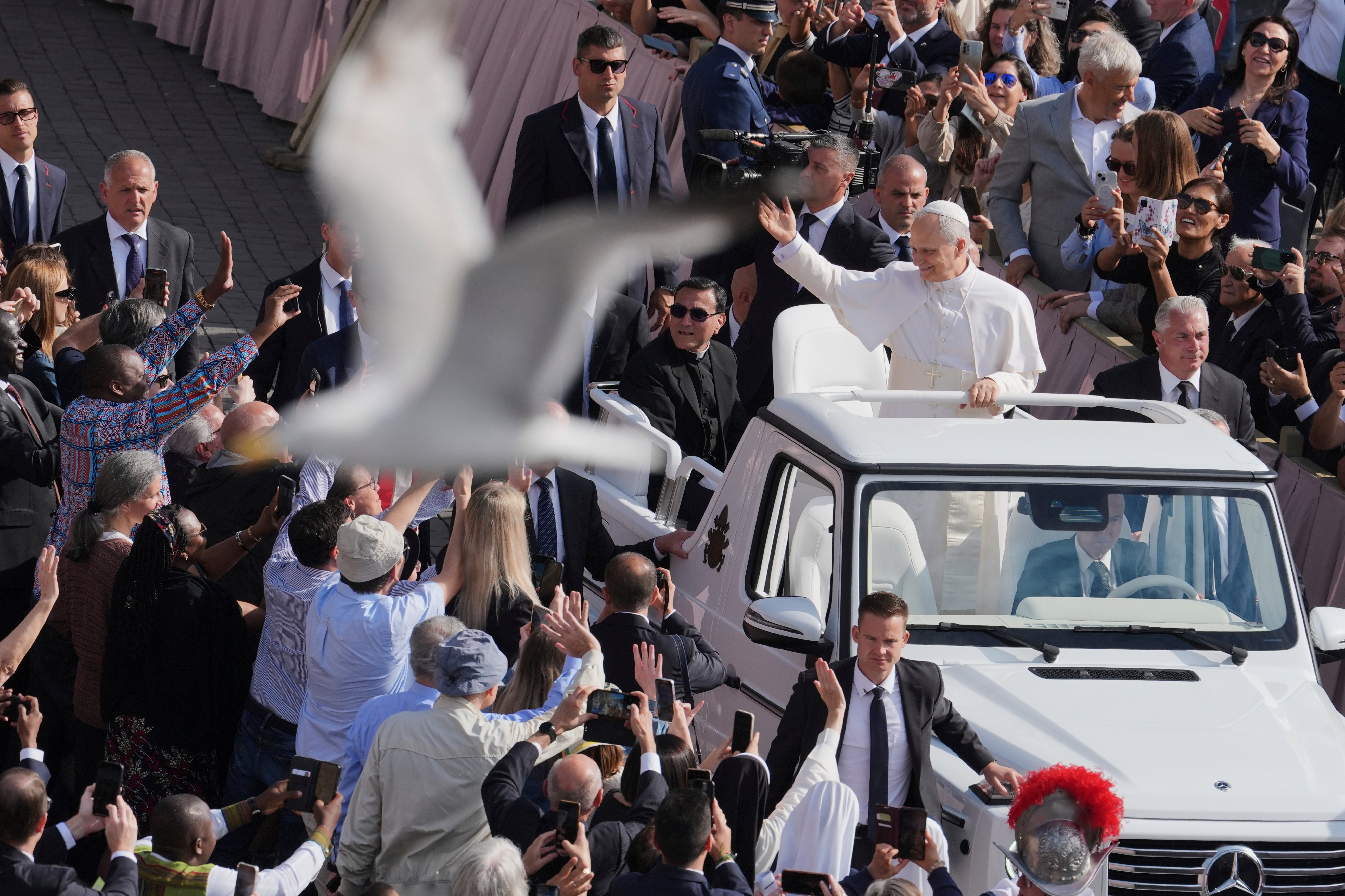 A bird flies by as Pope Leo XIV on his popemobile tours St. Peter's Square at the Vatican prior to the inaugural Mass of his pontificate, Sunday, May 18, 2025. (AP Photo/Jacquelyn Martin, Pool)
