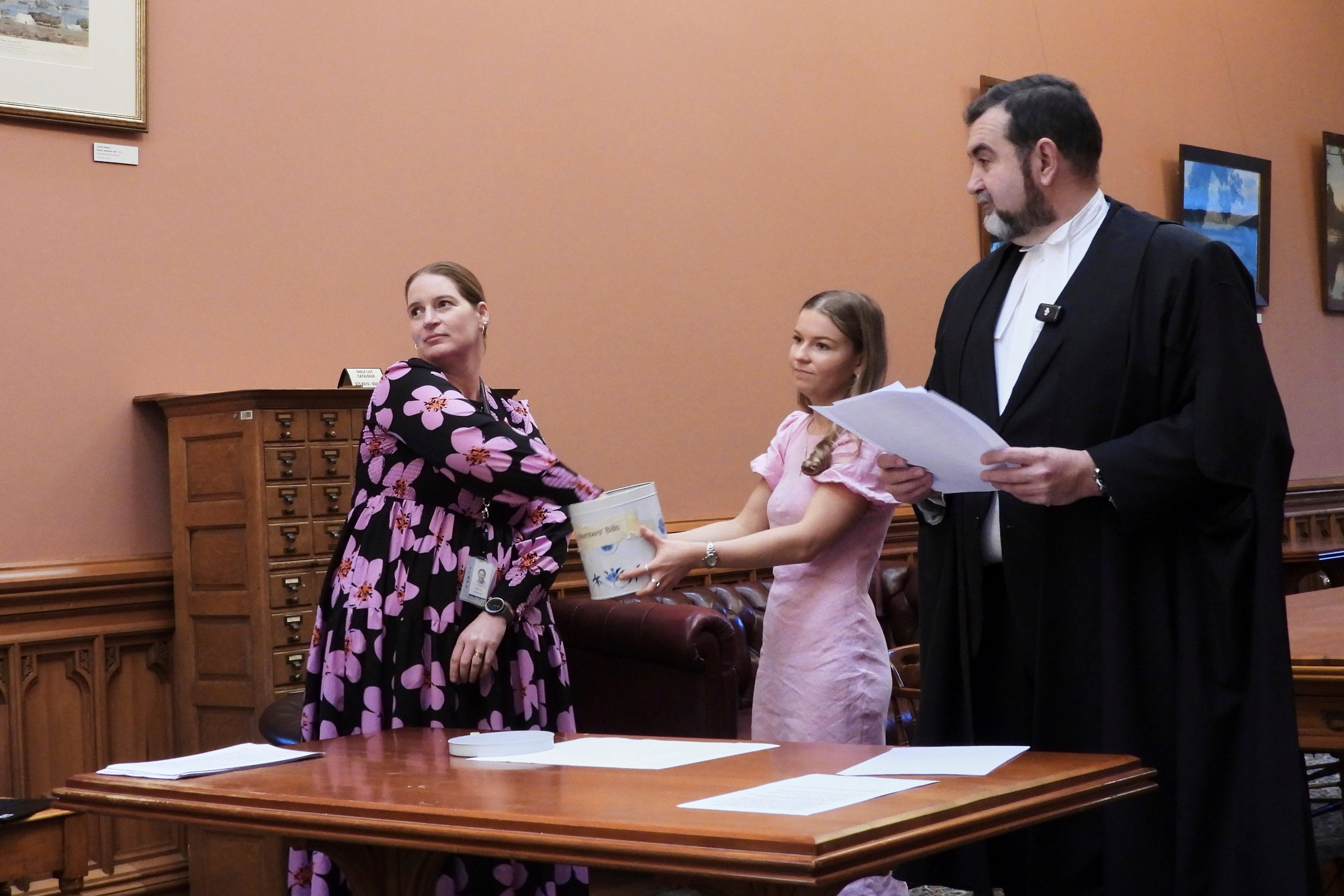 Parliamentary Service staffer Renee Beeson, left, draws a bingo token from the biscuit tin
