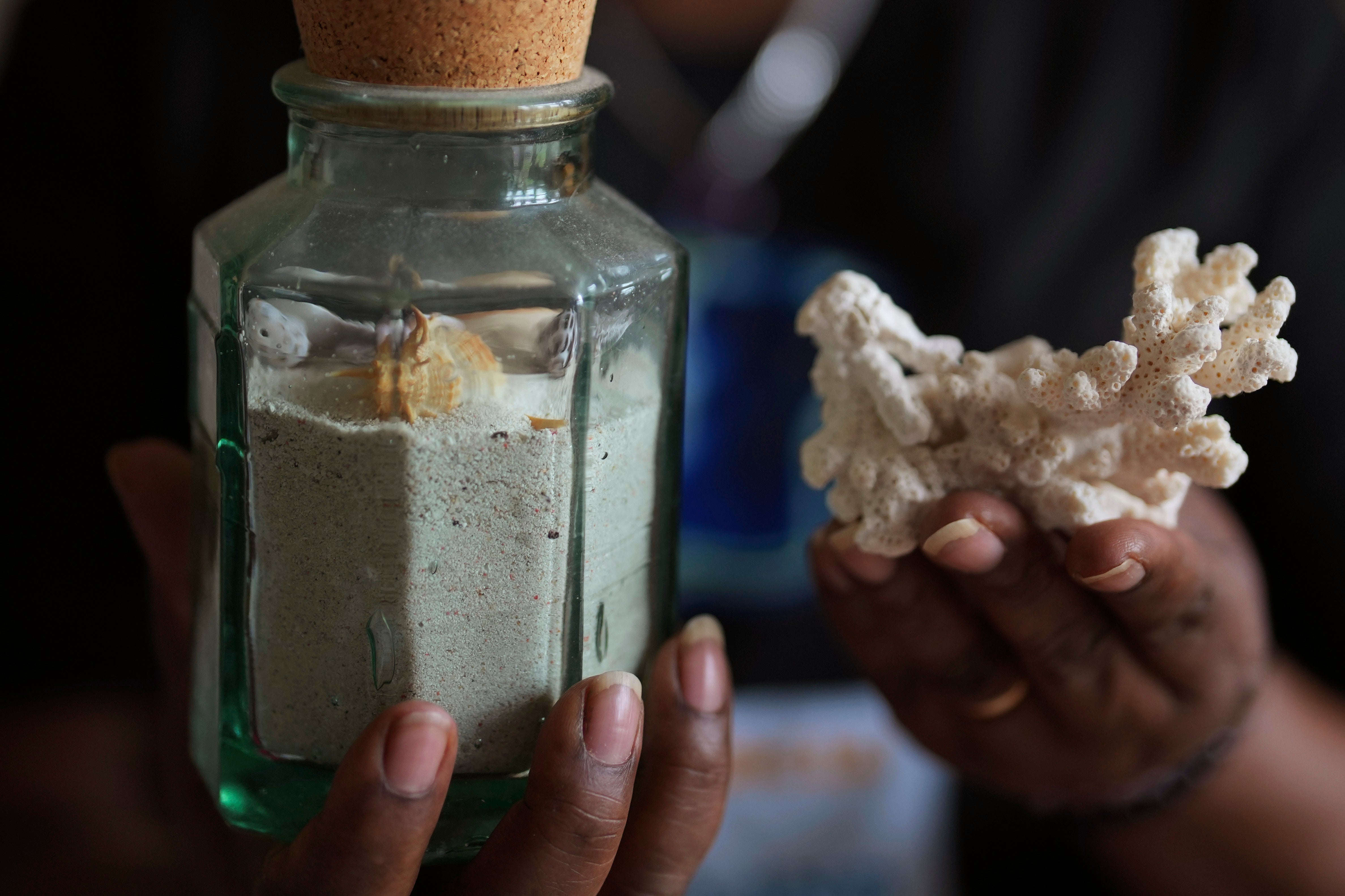 Chagossian Bernadette Dugasse shows sand and sea shells from the Chagos Islands during an interview with The Associated Press, at her home in London, Tuesday, March 25, 2025. (AP Photo/Kin Cheung)