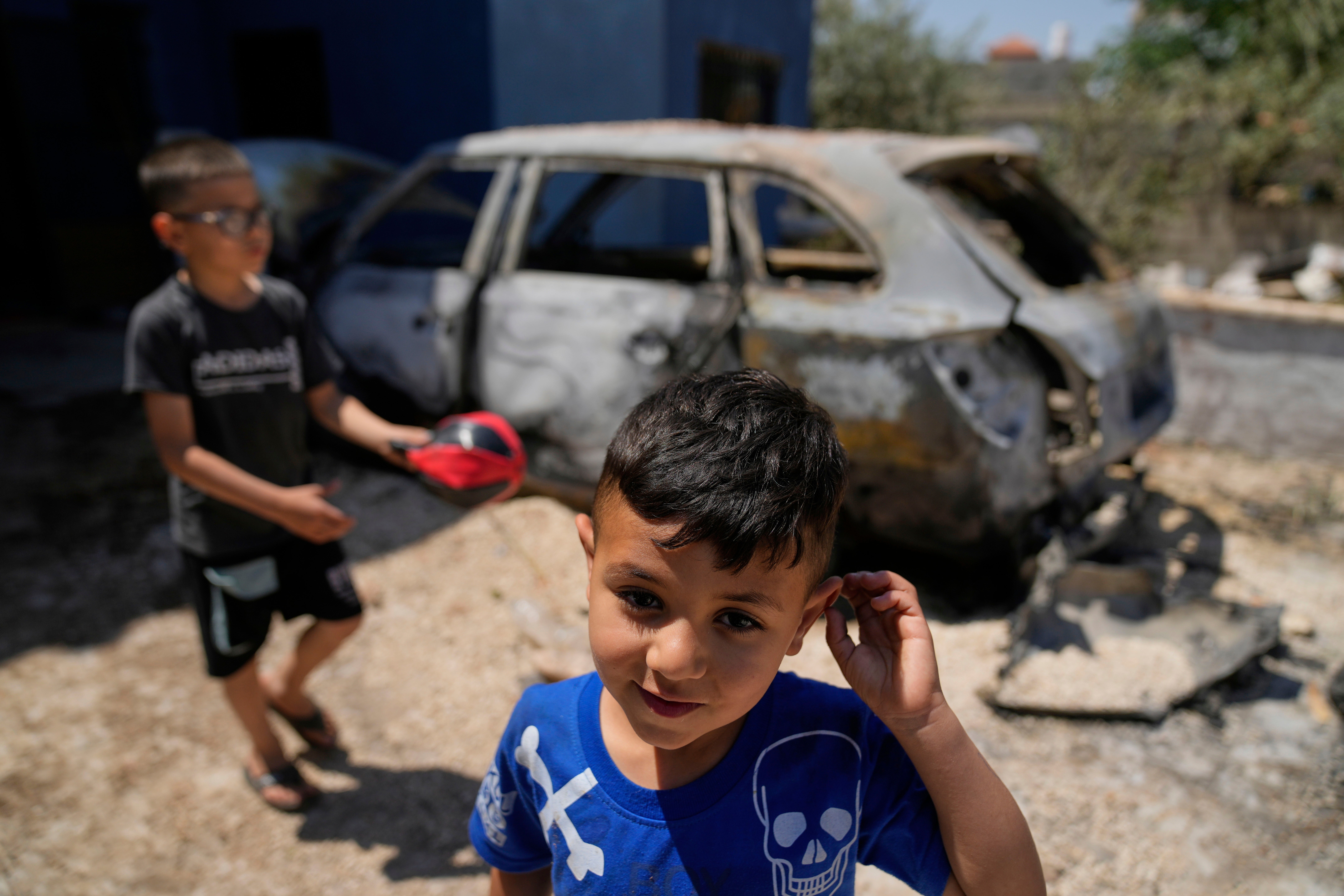 Palestinian boys play by their family's vehicle, which was burnt during an overnight attack by Israeli settlers and left several burnt vehicles and damaged homes, residents said, in the West Bank village of Bruqin, near Salfit, Friday, May 23, 2025