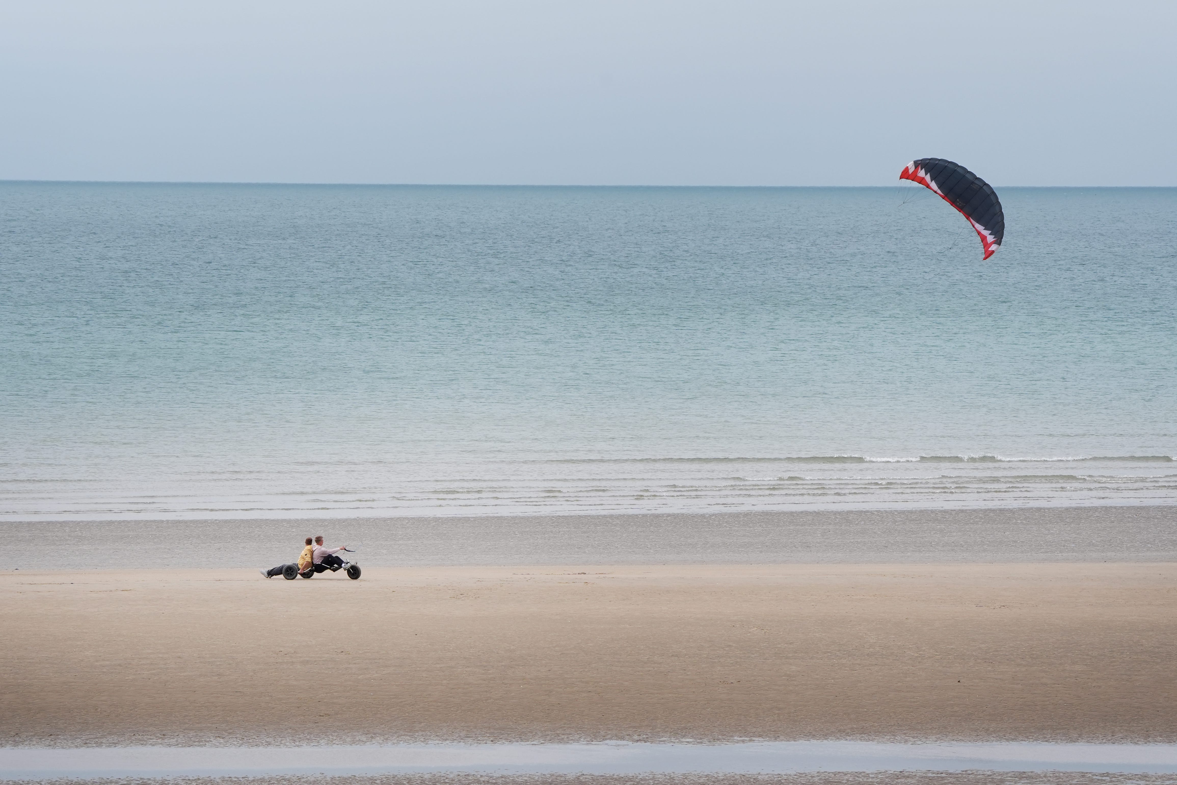 A kite buggy is raced along the beach during the cool windy conditions in Camber, East Sussex (Gareth Fuller/PA)