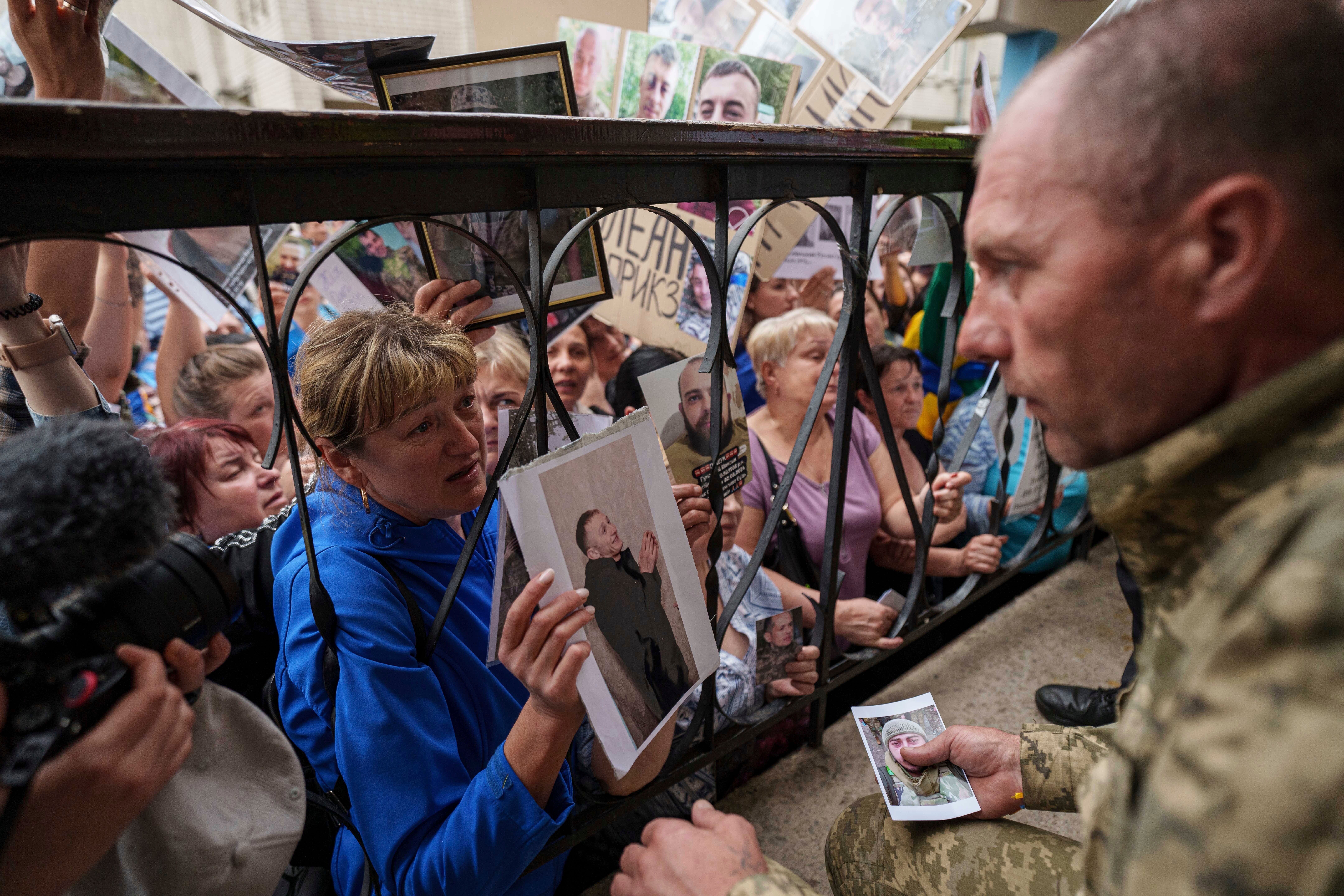 People show photos of their missed relatives to Ukrainian soldiers during a POWs exchange between Russia and Ukraine, in Chernyhiv region, Ukraine, Saturday, May 24, 2025. (AP Photo/Evgeniy Maloletka)