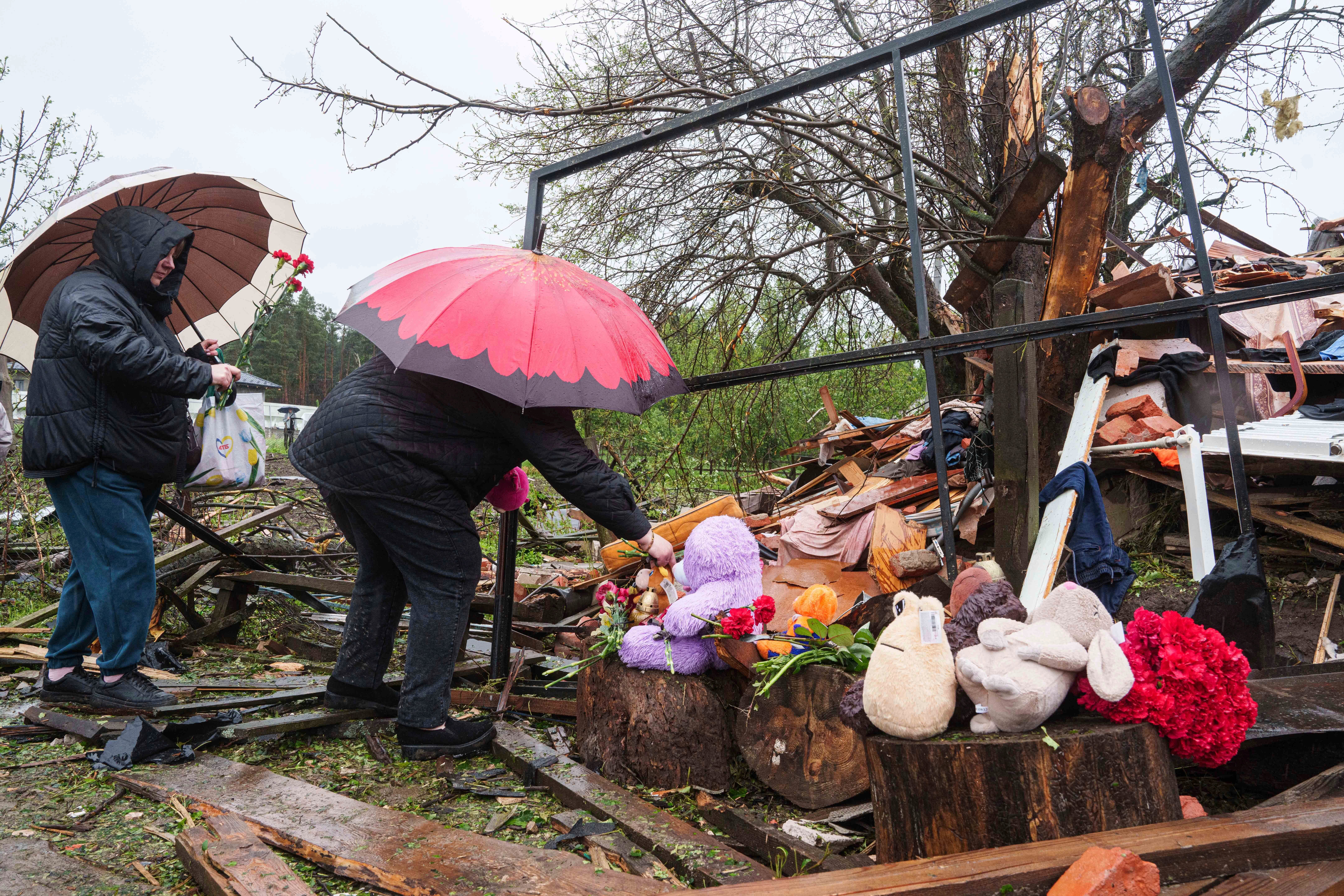 Women lay flowers by the rubble of a destroyed house where three children were killed by a Russian strike in Korostyshiv, Zhytomyr region, on Sunday