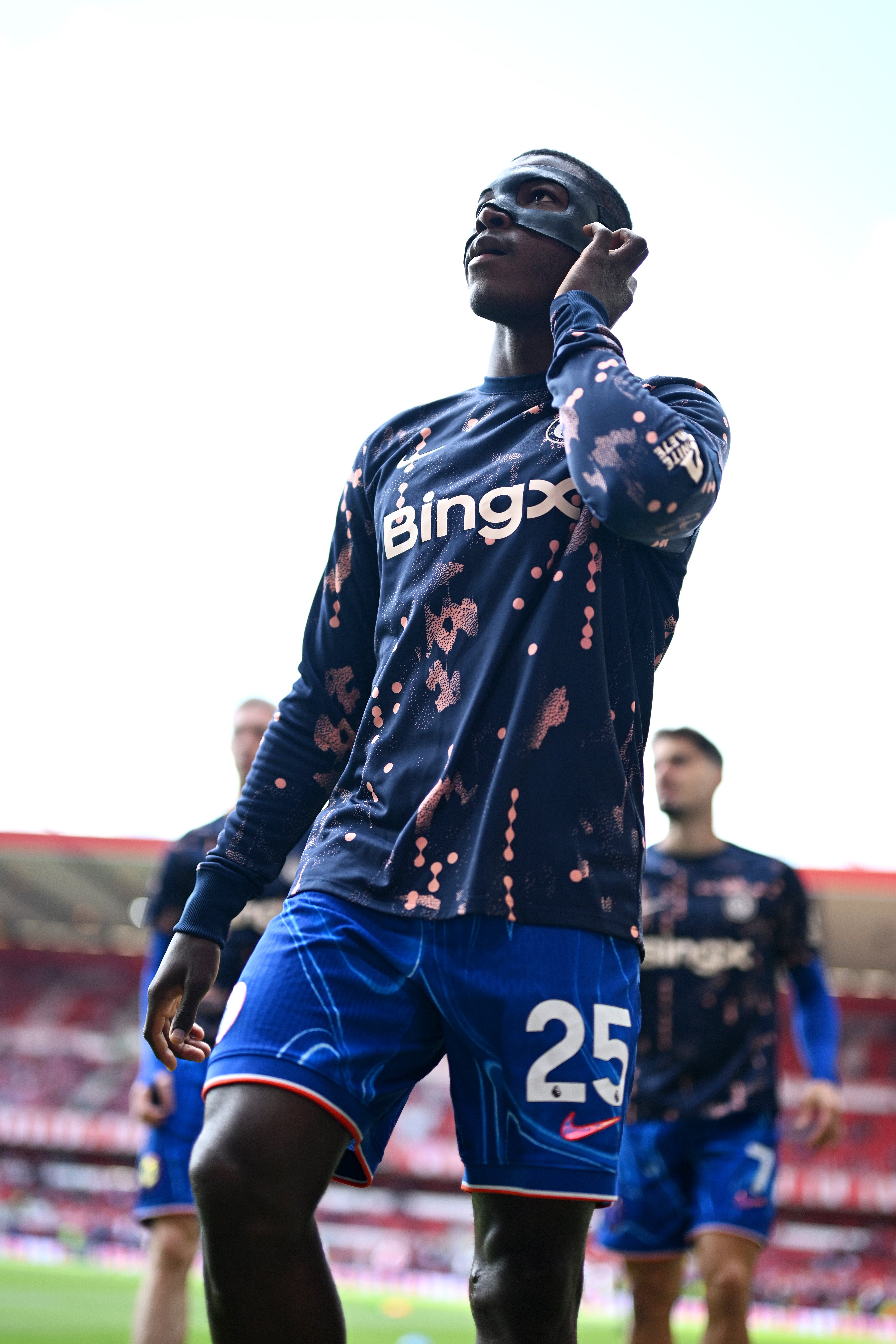 Moises caicedo z Chelsea se zahřívá, zatímco nosí černou ochrannou obličejovou masku