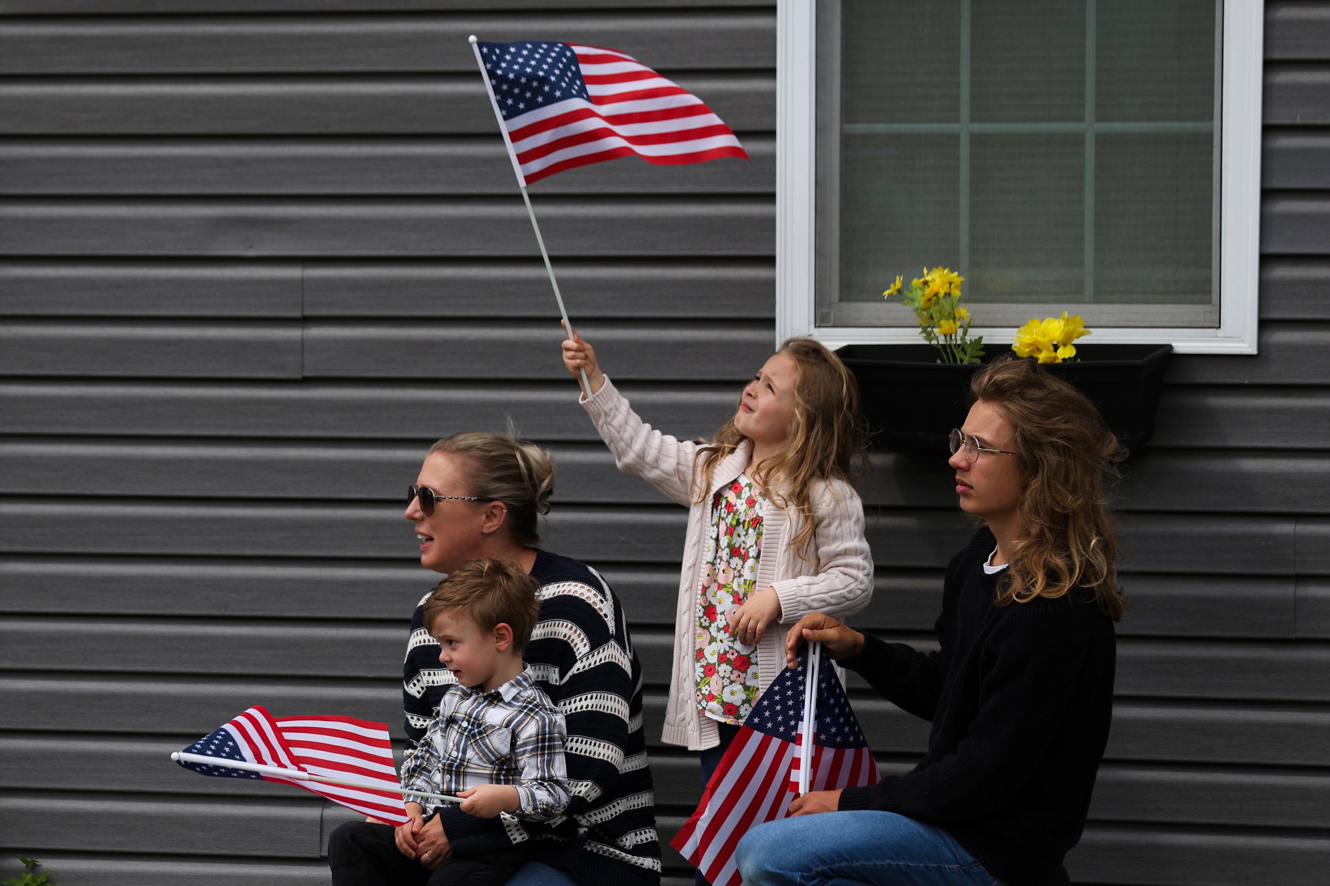 Fallon Haight, 5, center, waves an American flag while waiting for the procession carrying the remains of World War II U.S. Army Air Forces Staff Sgt. Eugene Darrigan to pass through, Saturday, May 24, 2025, in Wappingers Falls, N.Y. Darrigan was buried in his hometown after his remains were recovered from the World War II bomber that crashed into the water off the coast of New Guinea on March 11, 1944. (AP Photo/Heather Khalifa)