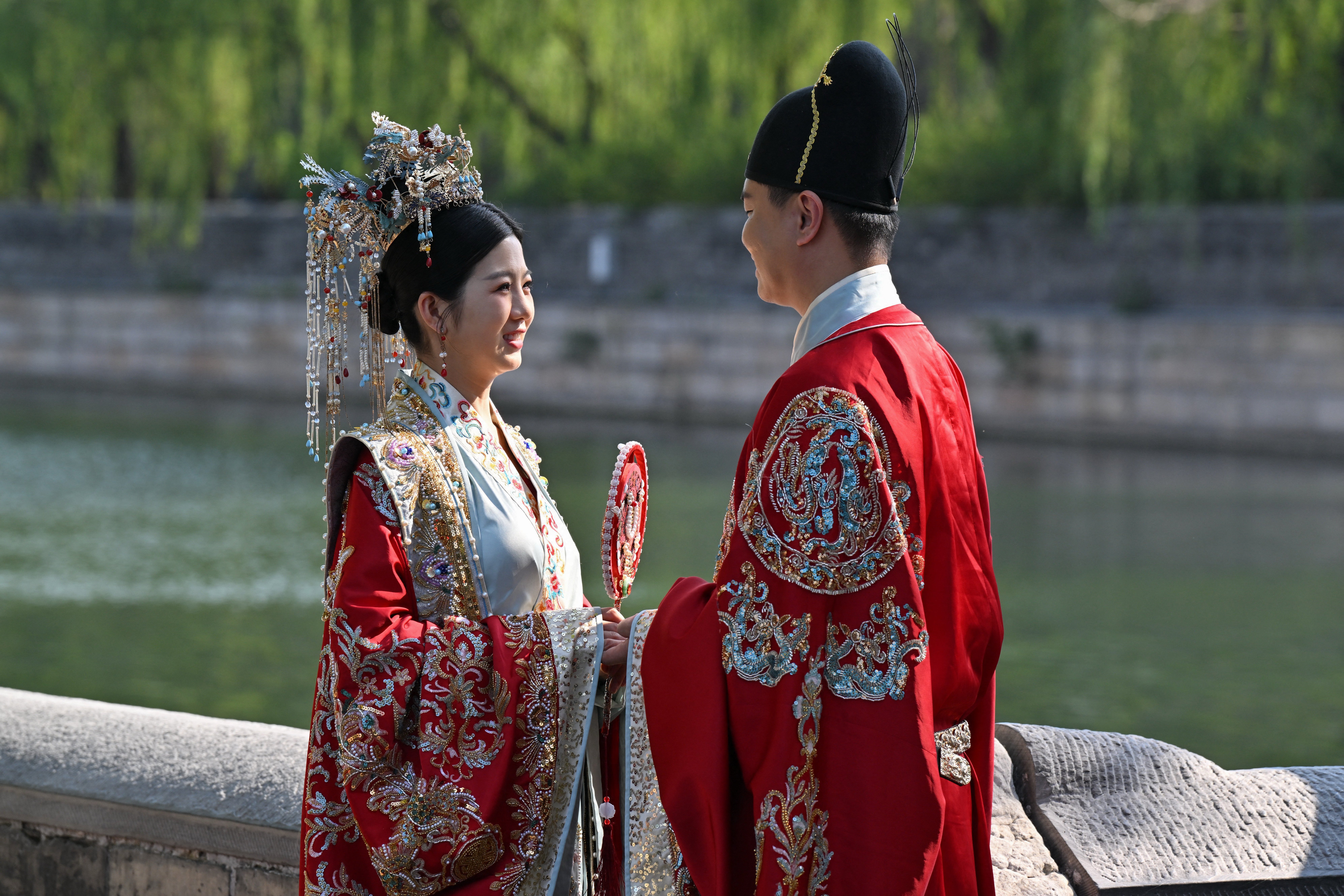 A couple in traditional costumes pose for a wedding photo shoot at the Forbidden City in Beijing