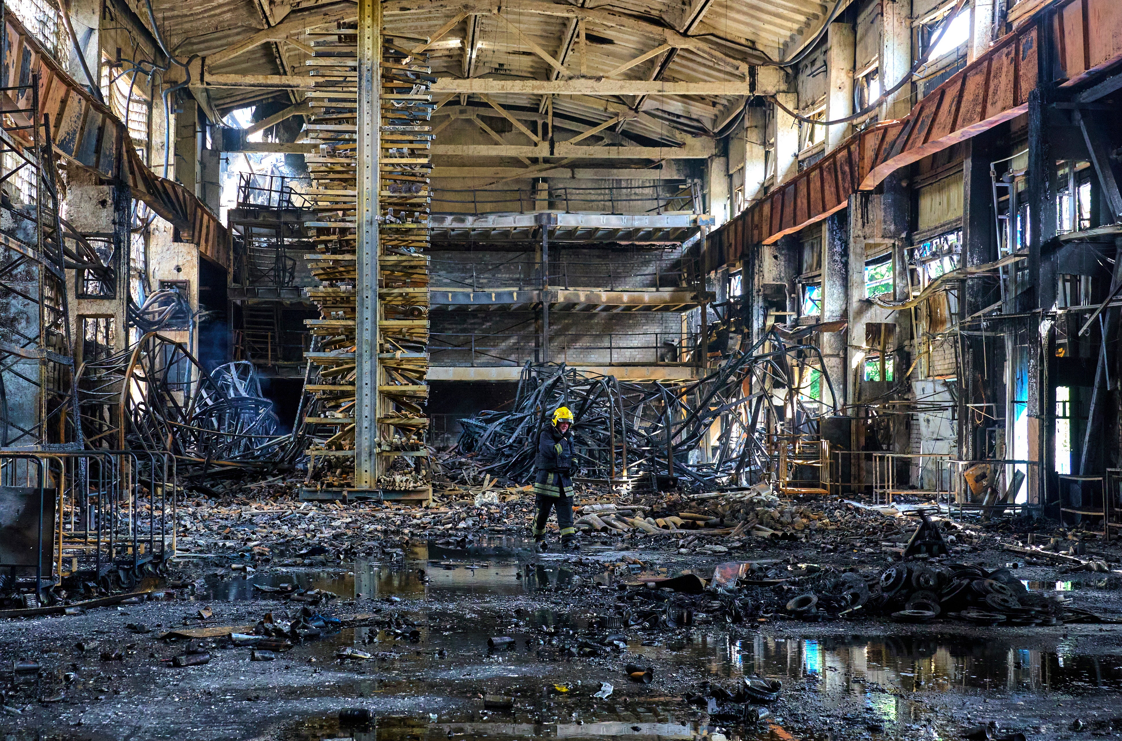 Ukrainian firefighters and rescuers work at the site of a damaged storage facility at a private factory following an overnight attack in Vasyshcheve, near Kharkiv, Ukraine