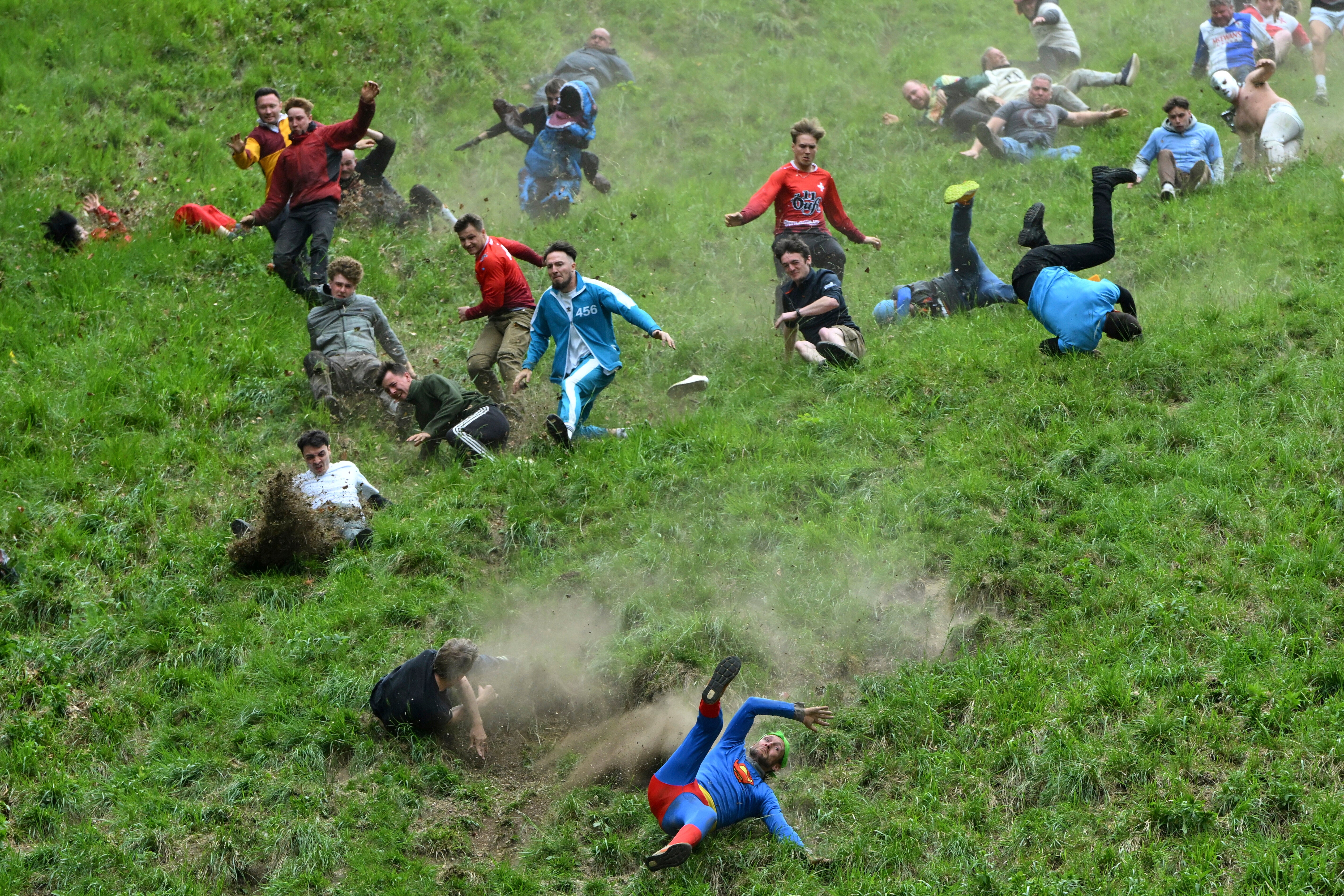 Participants compete in the men's downhill race category of the traditional annual Cheese Rolling contest at Cooper's Hill in Brockworth, Gloucestershire