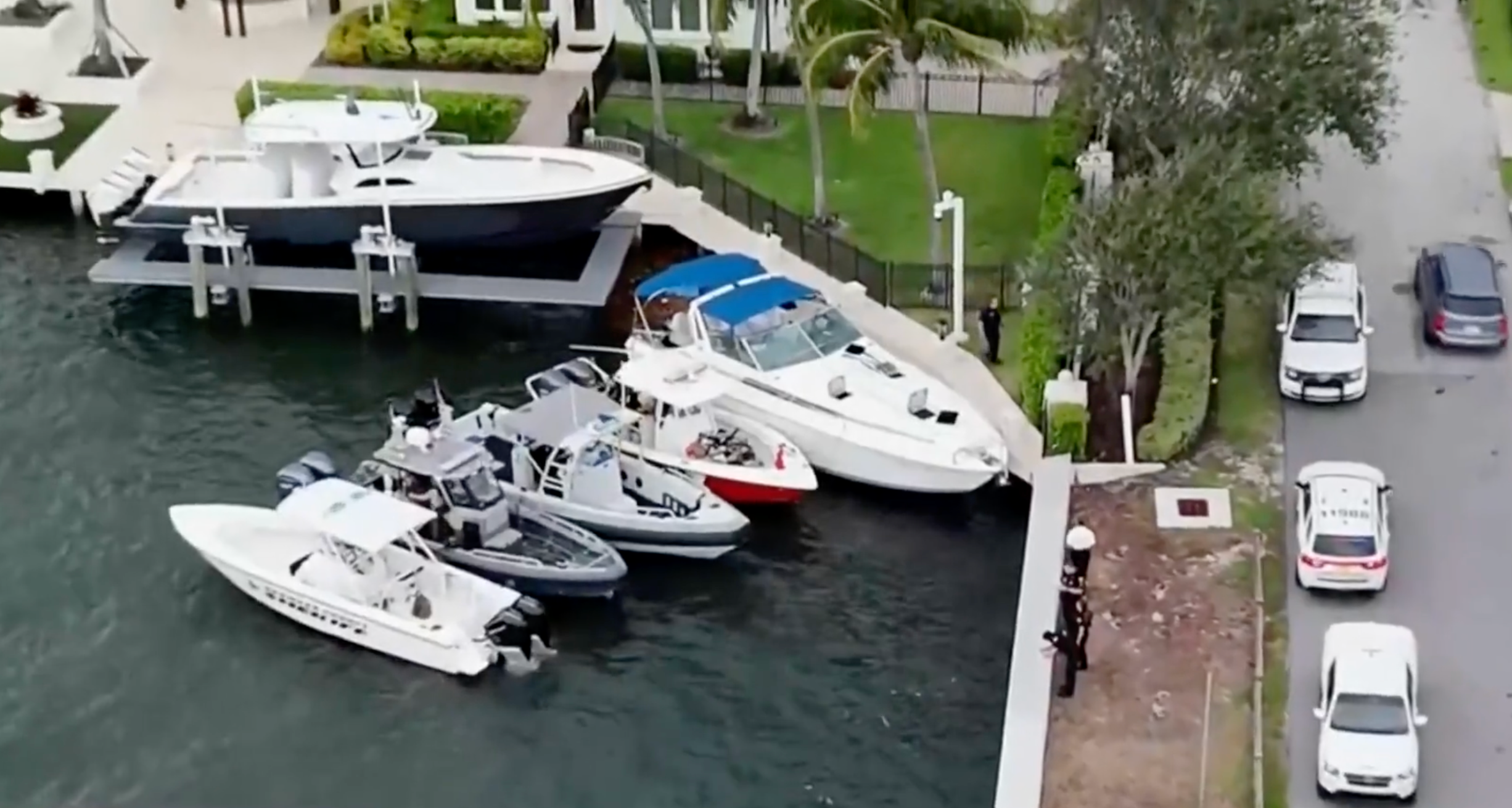 Investigators examine a boat, dockside with blue cover, whose engine exploded with 13 people on board in Fort Lauderdale, Florida,