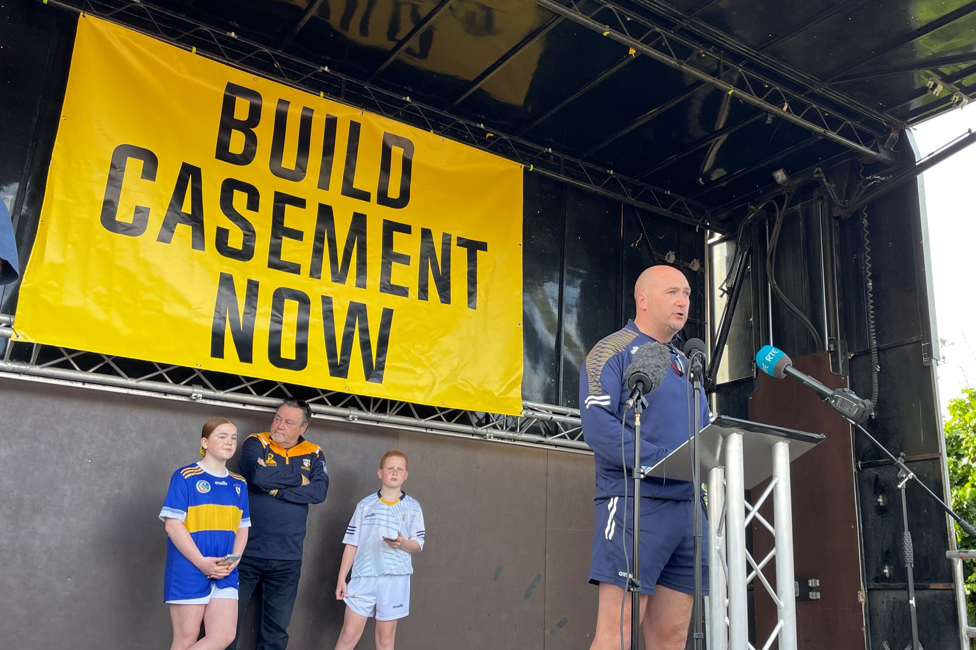 Kevin Gamble, chairman of South Antrim GAA, speaking to the thousands of gaelic games players and supporters who marched to the derelict Casement Park stadium in Belfast (PA)