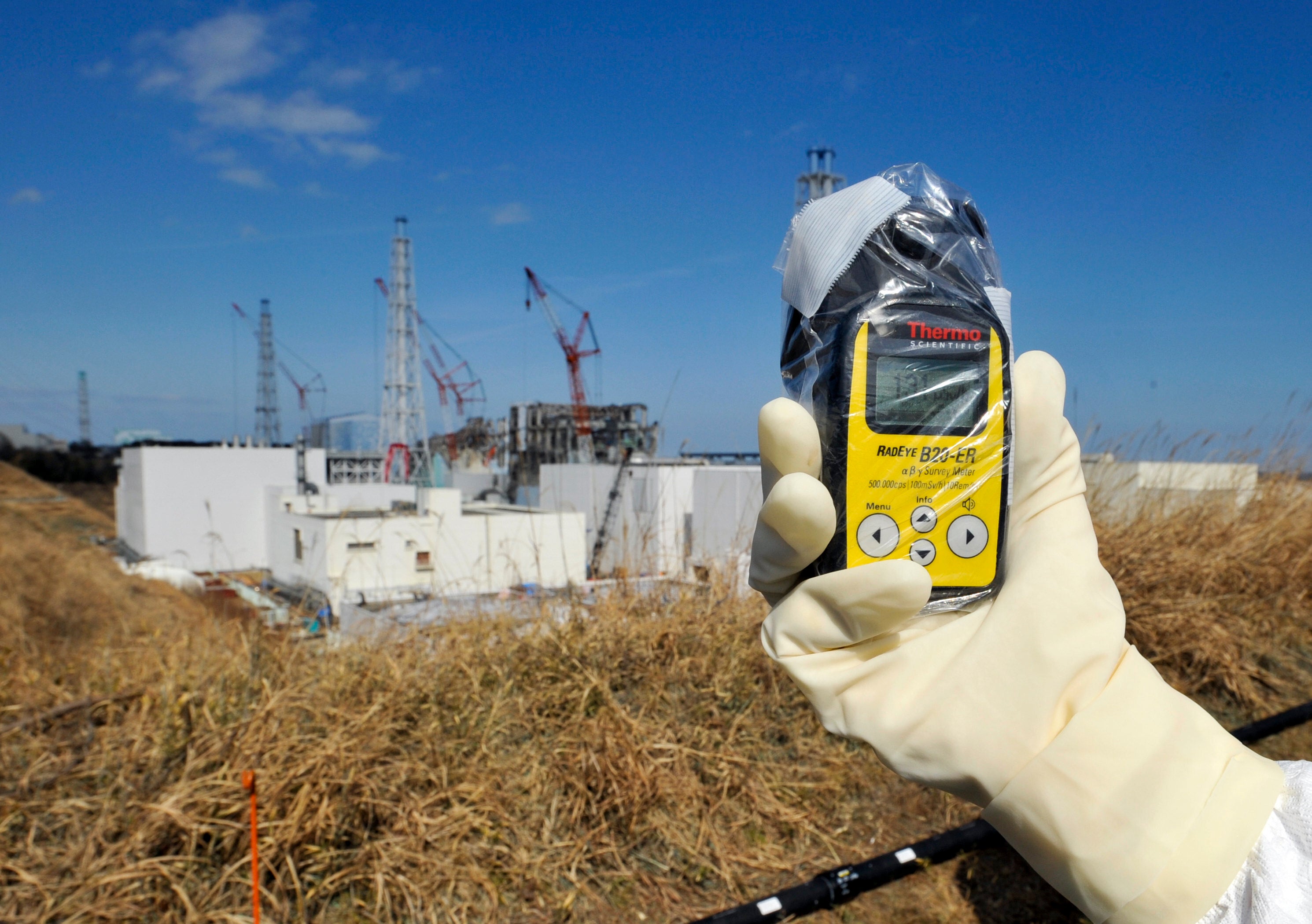 A worker holds a radioactivity monitor near the Fukushima plant