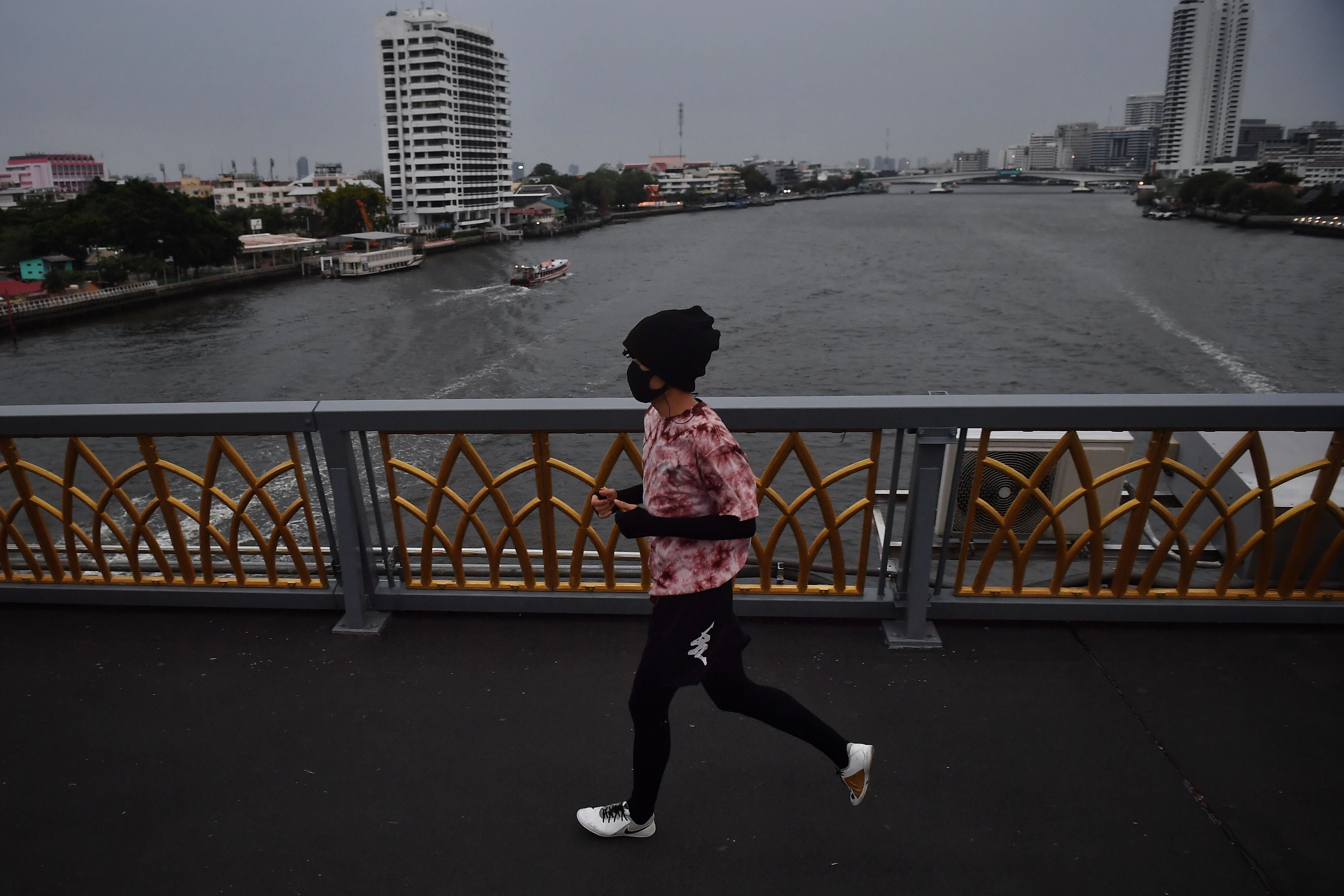 Representative. A runner runs on a bridge crossing the Chao Praya River in Bangkok, Thailand