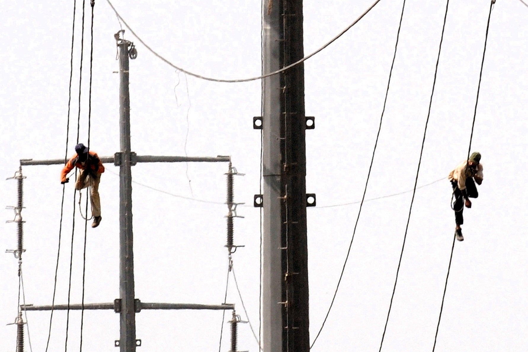 Pakistani technicians work on high voltage power lines in Karachi on 11 August, 2009