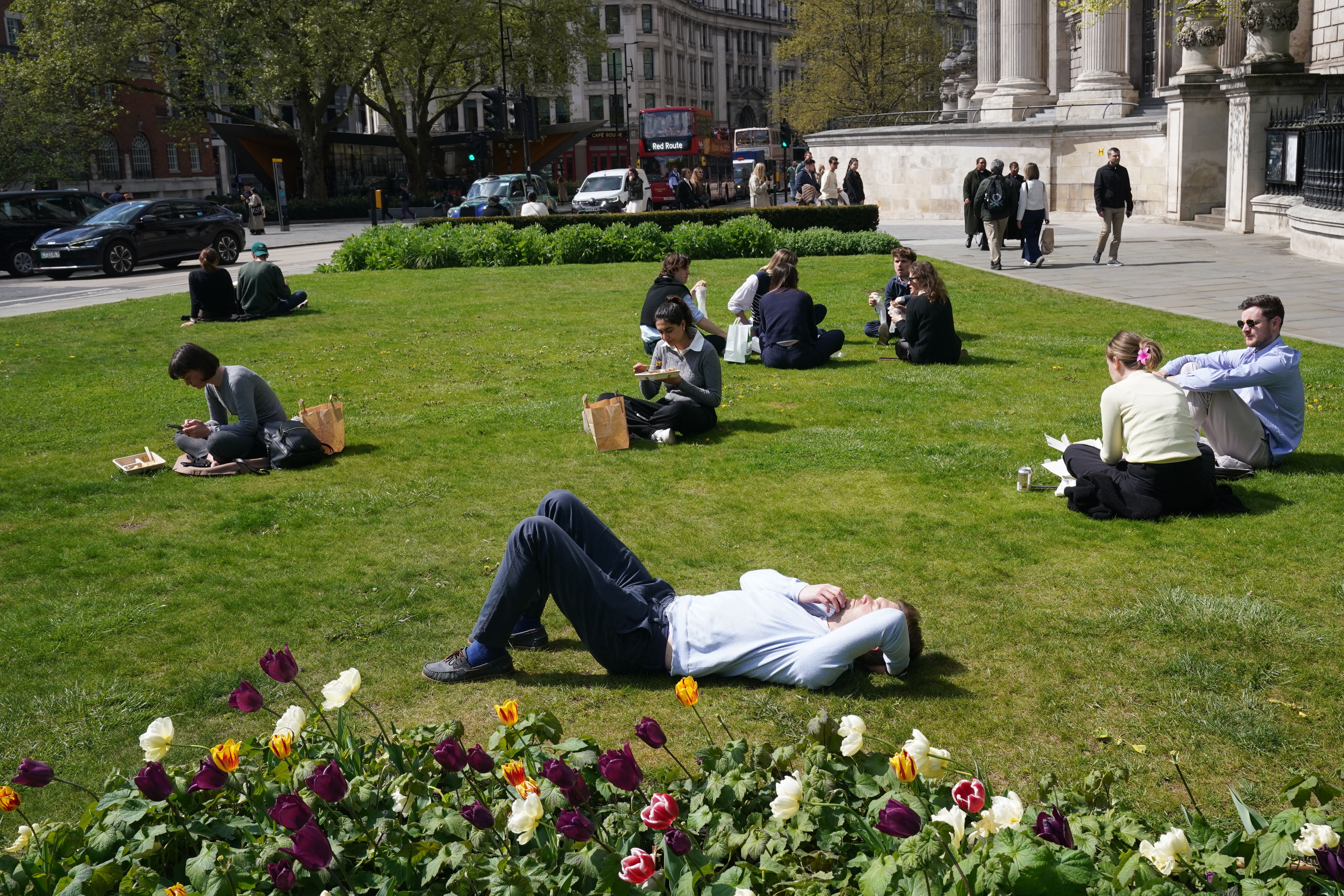 People enjoy the sunshine outside St Paul’s Cathedral in London