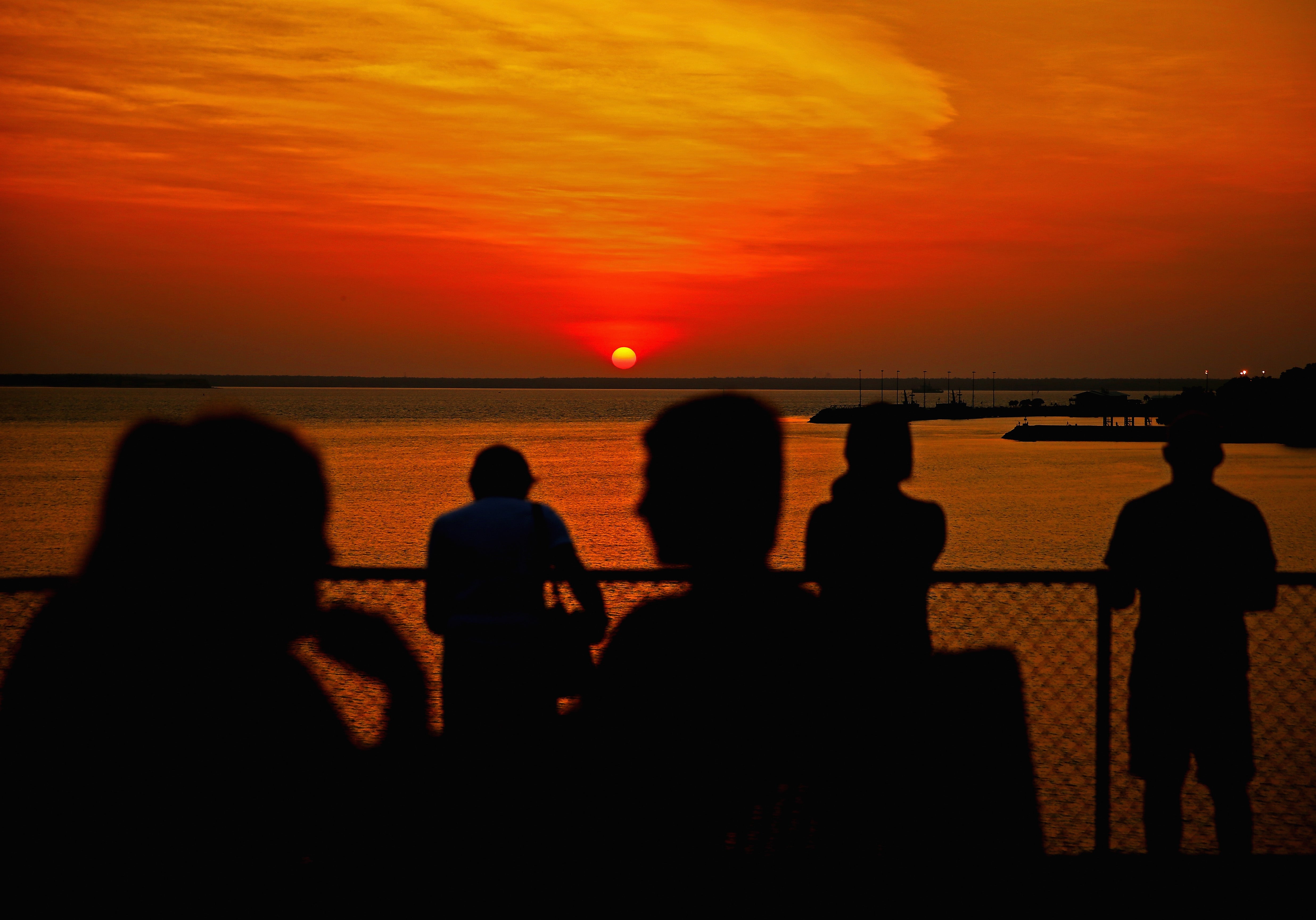 People watch the sunset over Port Darwin from Bicentennial Park in Darwin, Australia