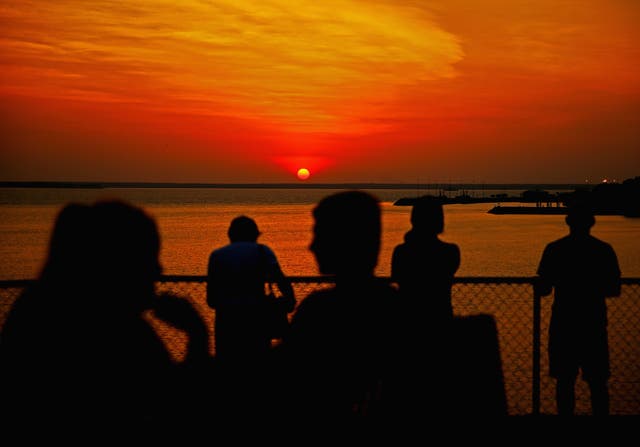 <p>People watch the sunset over Port Darwin from Bicentennial Park in Darwin, Australia</p>