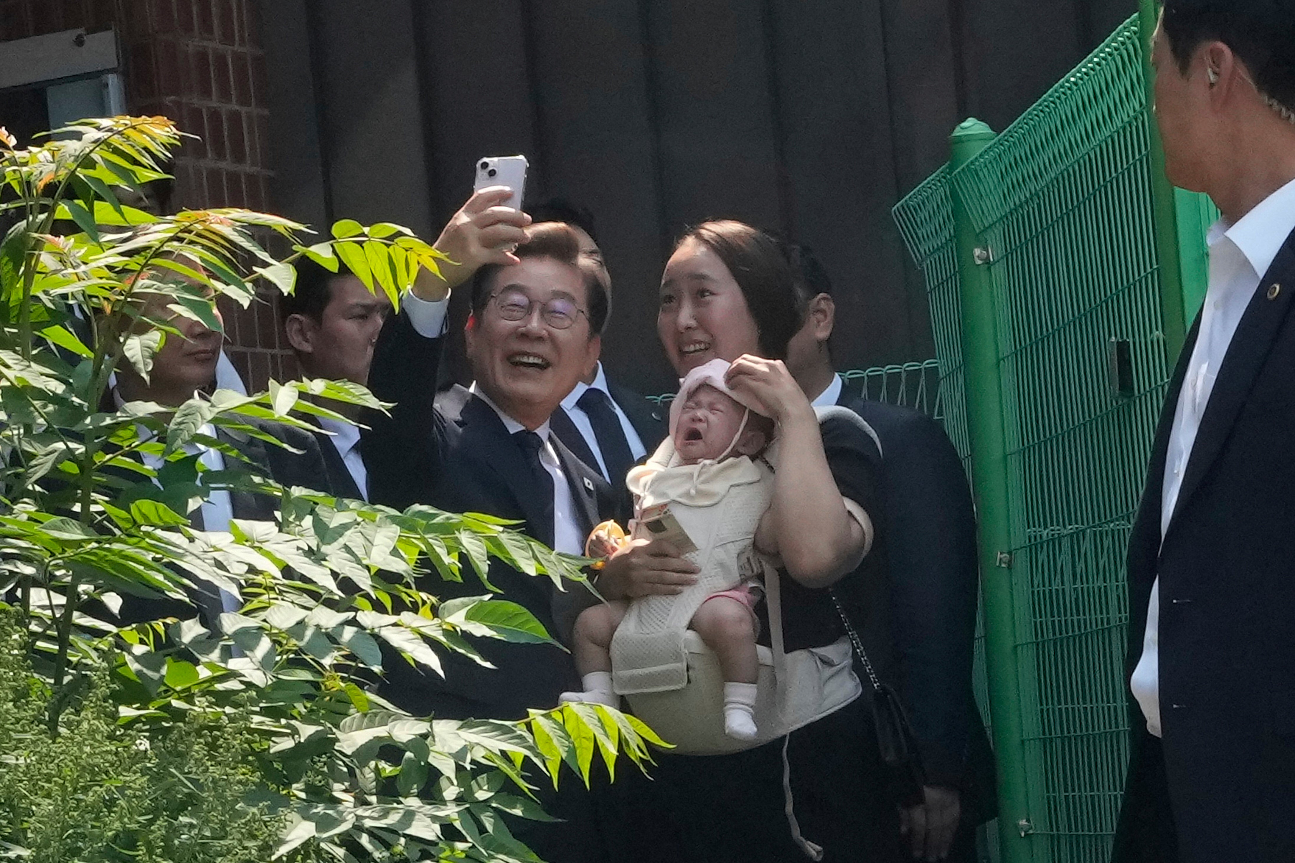 South Korean Democratic Party candidate Lee Jae Myung, left, takes a photo with a woman after casting his early vote for the 3 June presidential election in Seoul