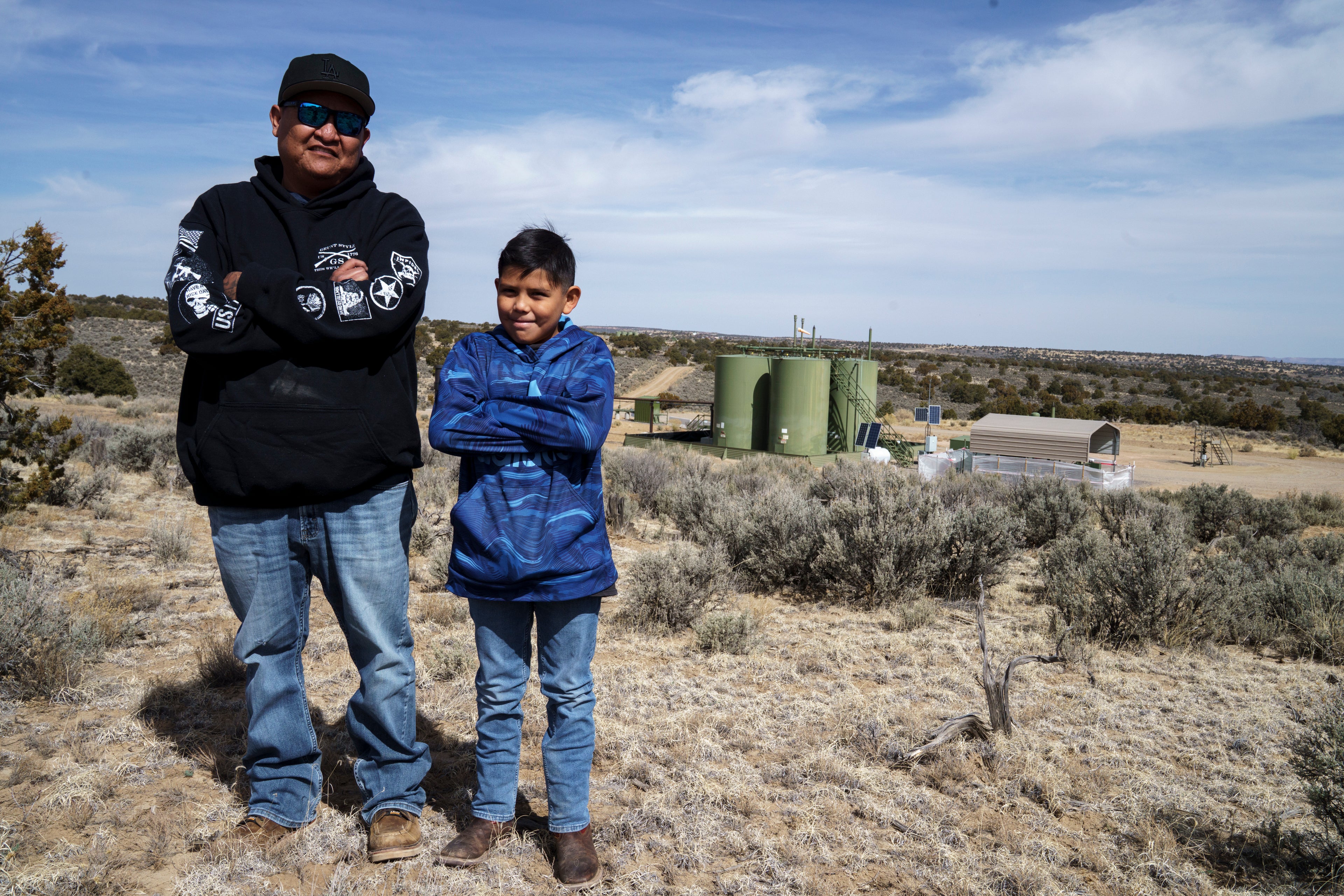 Billton Werito and his son Amari stand in front of a drilling pad near their house in an area where oil and gas drilling close to a local elementary school is causing students, including Amari, to miss school from negative health effects according to Werito, in Counselor, N.M., Navajo Nation