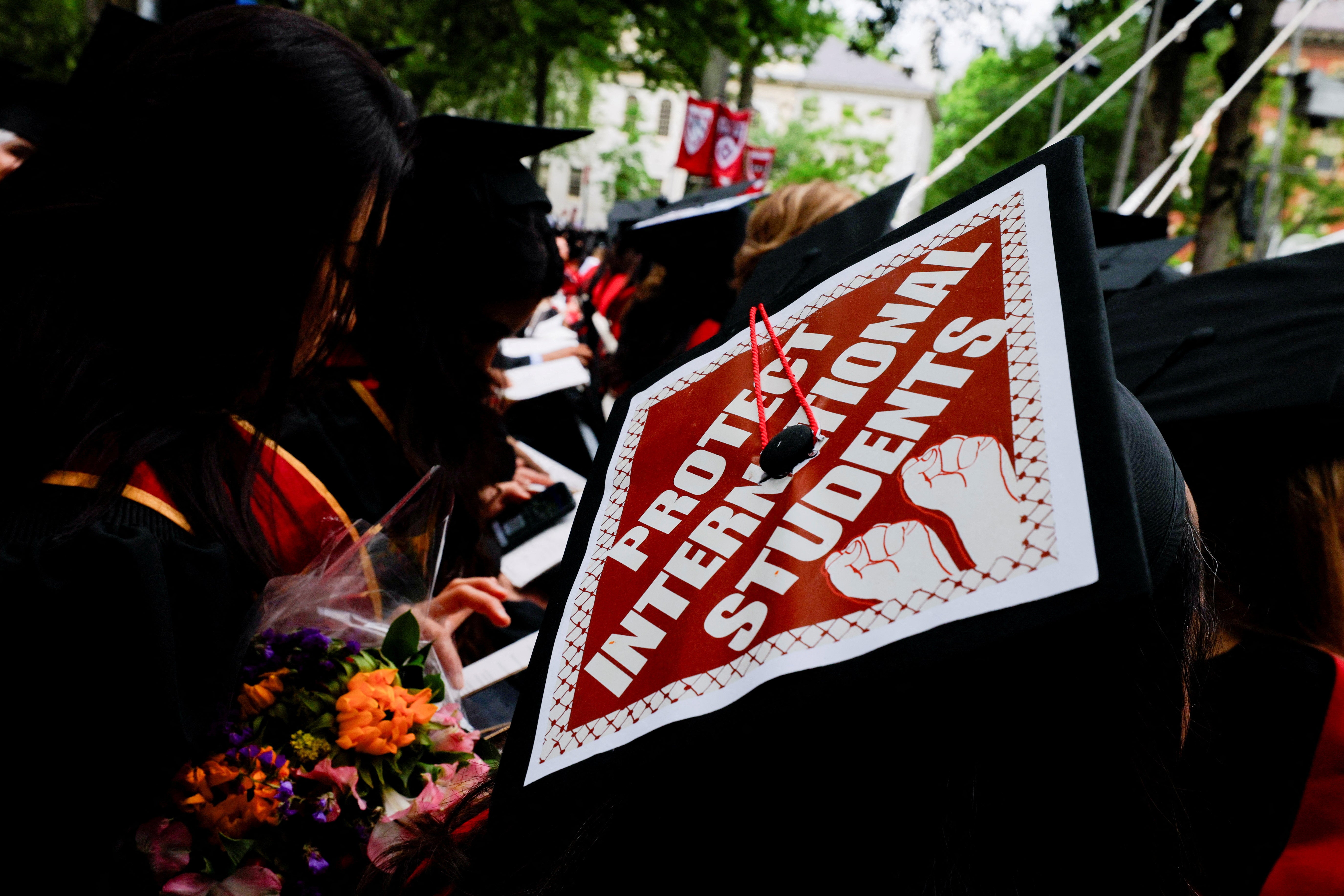 A graduating student wears their hat, decorated with a statement of support for international students, during Harvard University’s commencement ceremonies on May 29