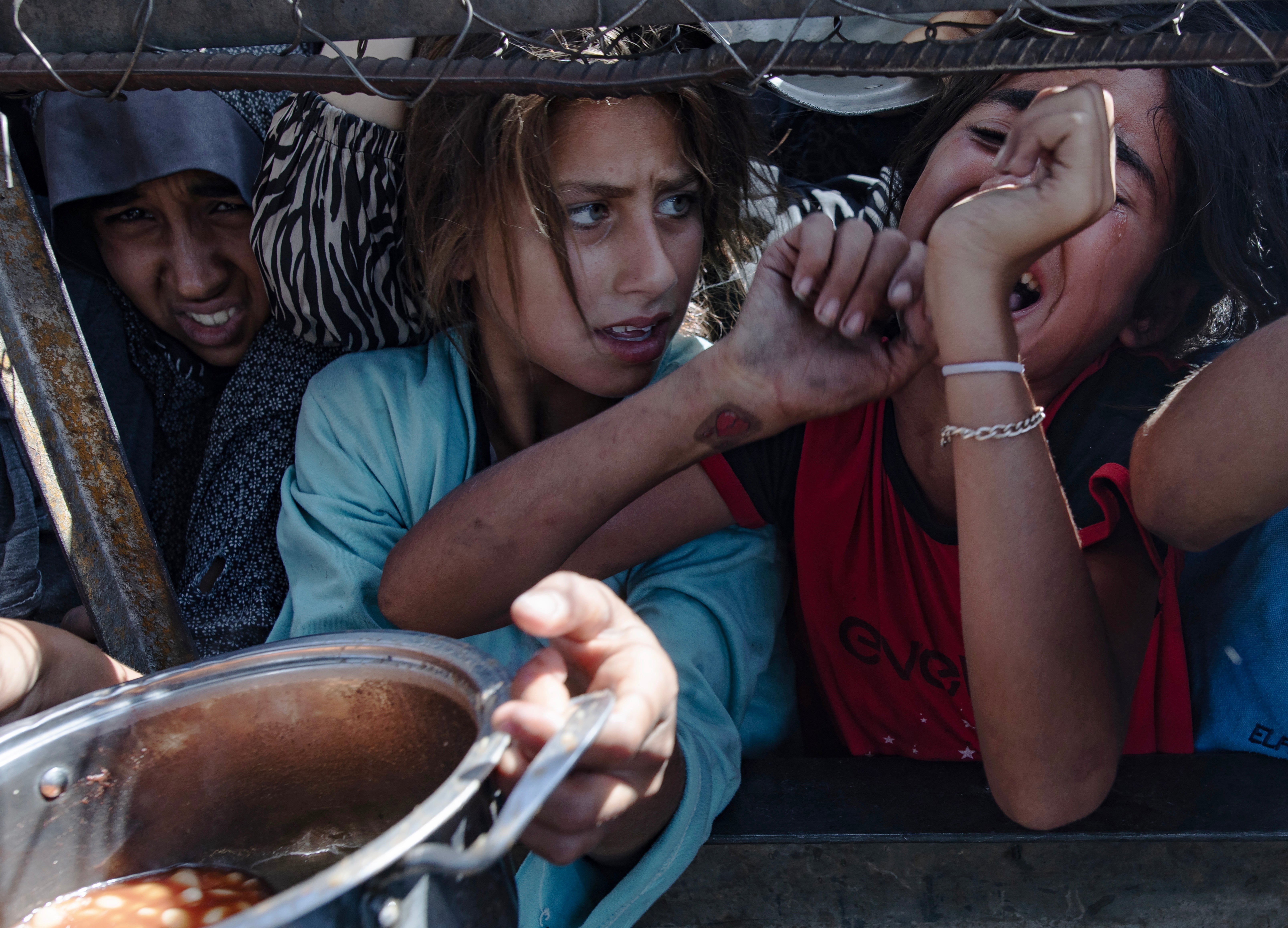 Girls wait to receive food at a charity kitchen in Khan Younis