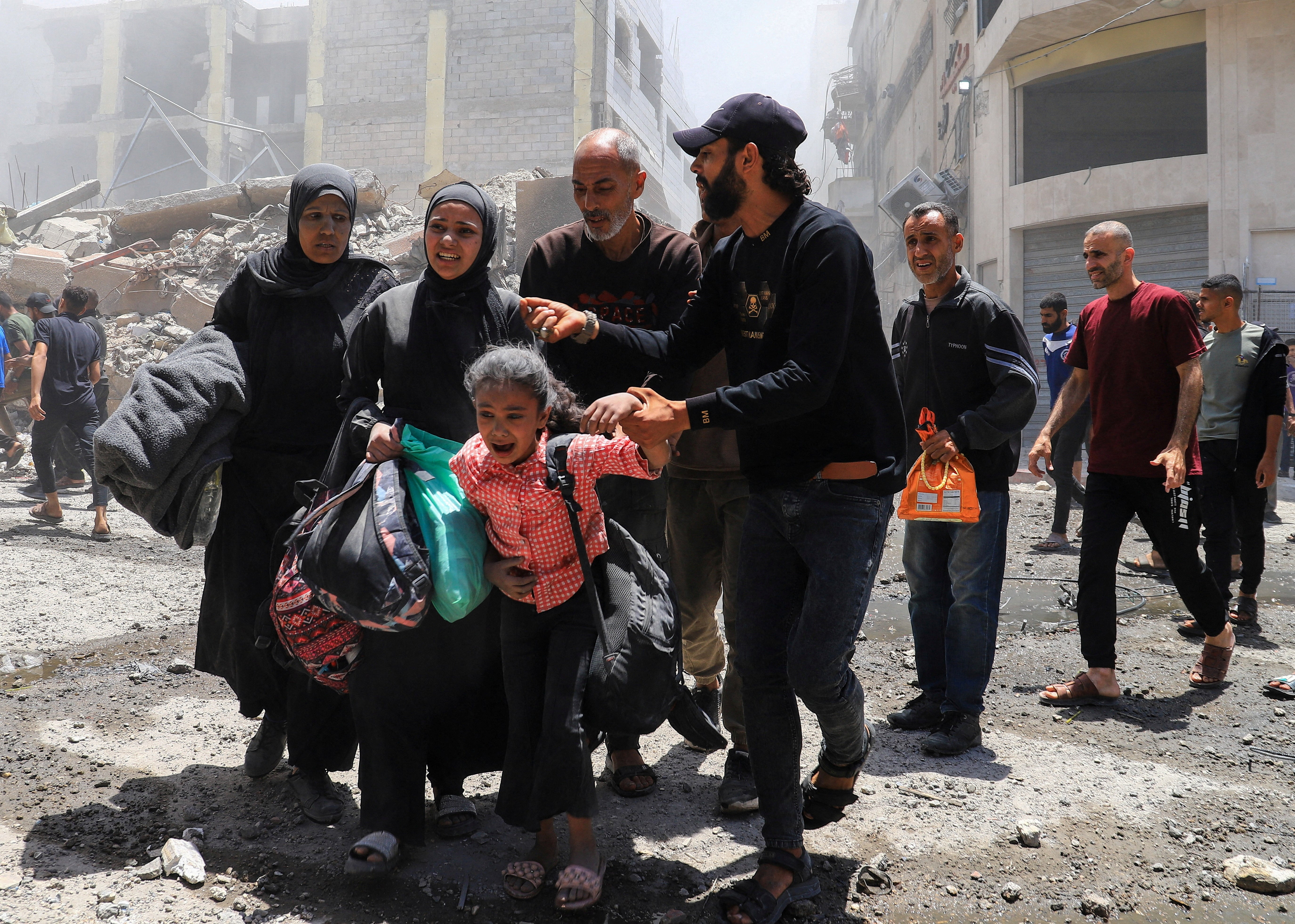 Palestinians evacuate in the aftermath of an Israeli strike on a house in Gaza City on Friday