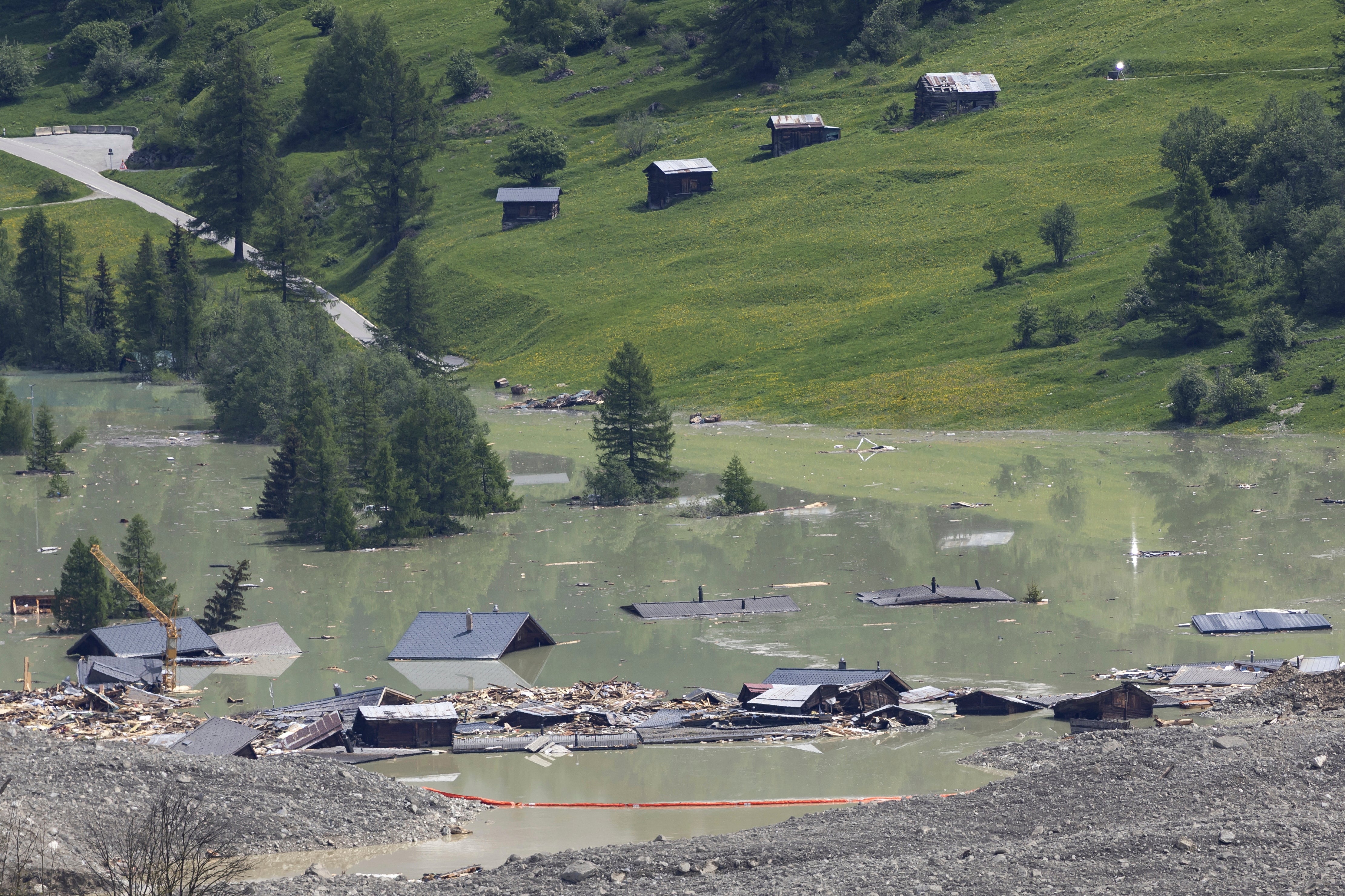 SwitzeCheck dams set up on the water from the Lonza river flows over the mud and stone, after the formation of a lake by the last houses of the village of Blatten, Switzerland