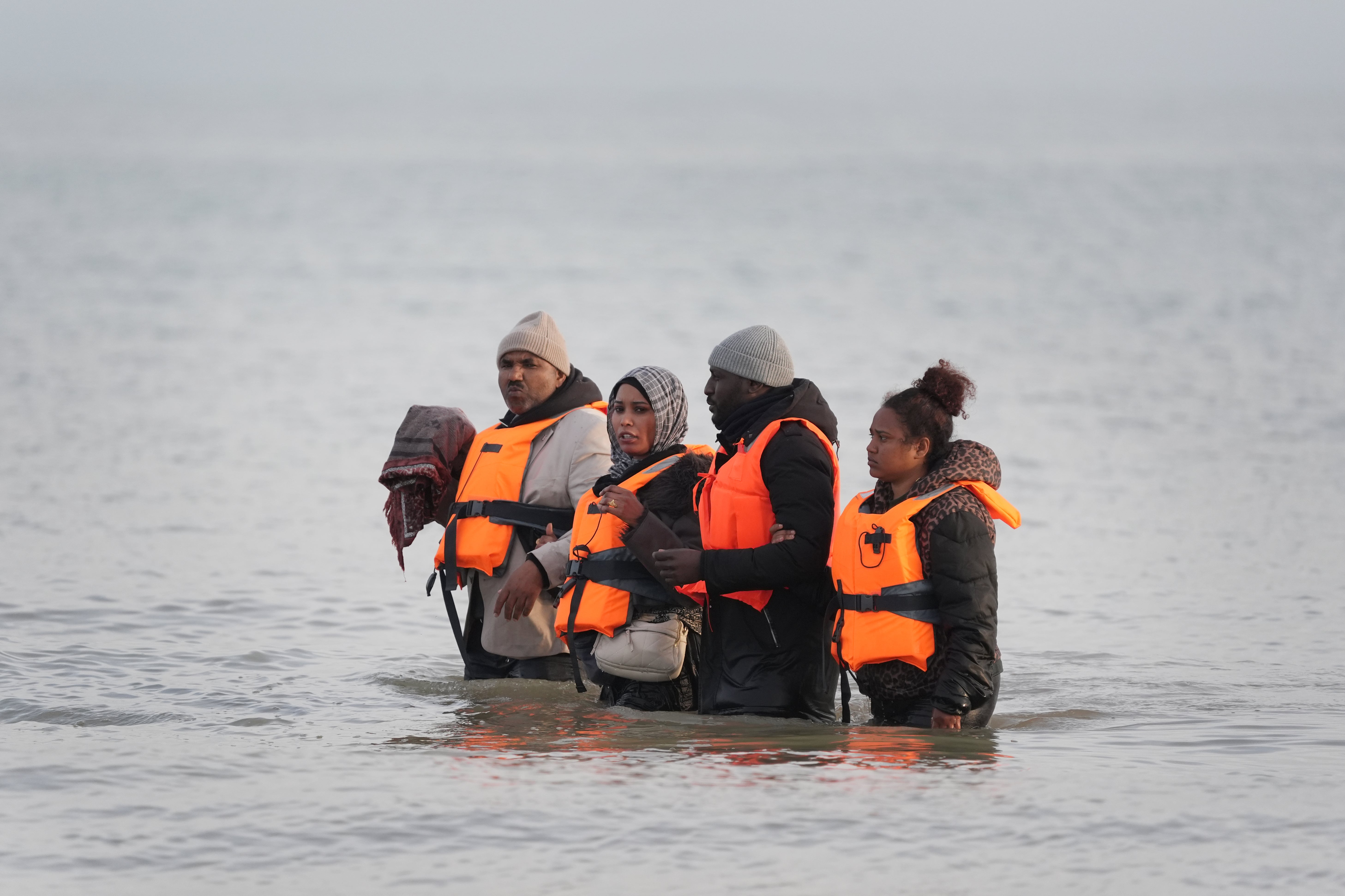 People thought to be migrants wade through the sea at Gravelines awaiting a boat