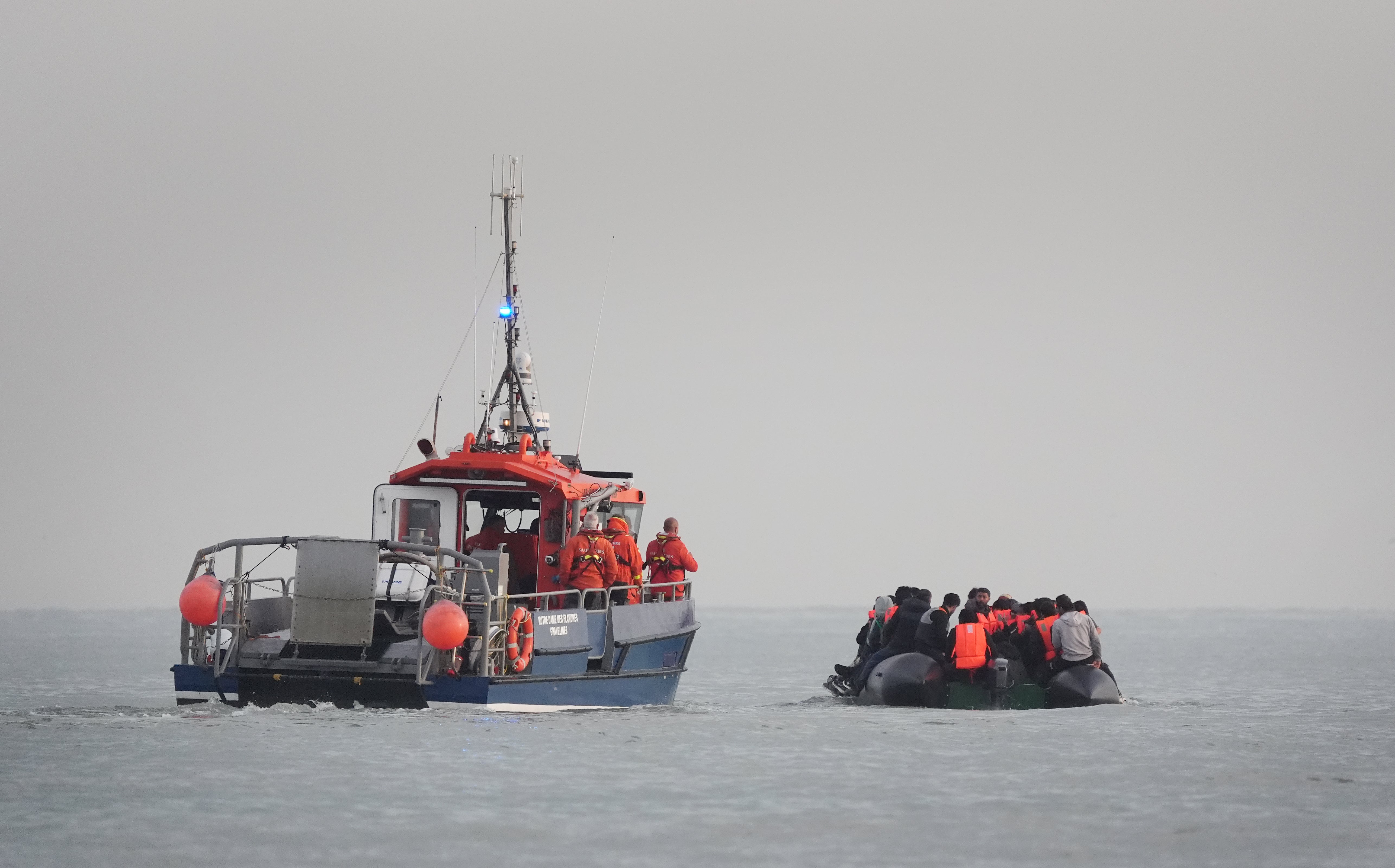 French authorities escort people thought to be migrants onboard a small boat leaving France
