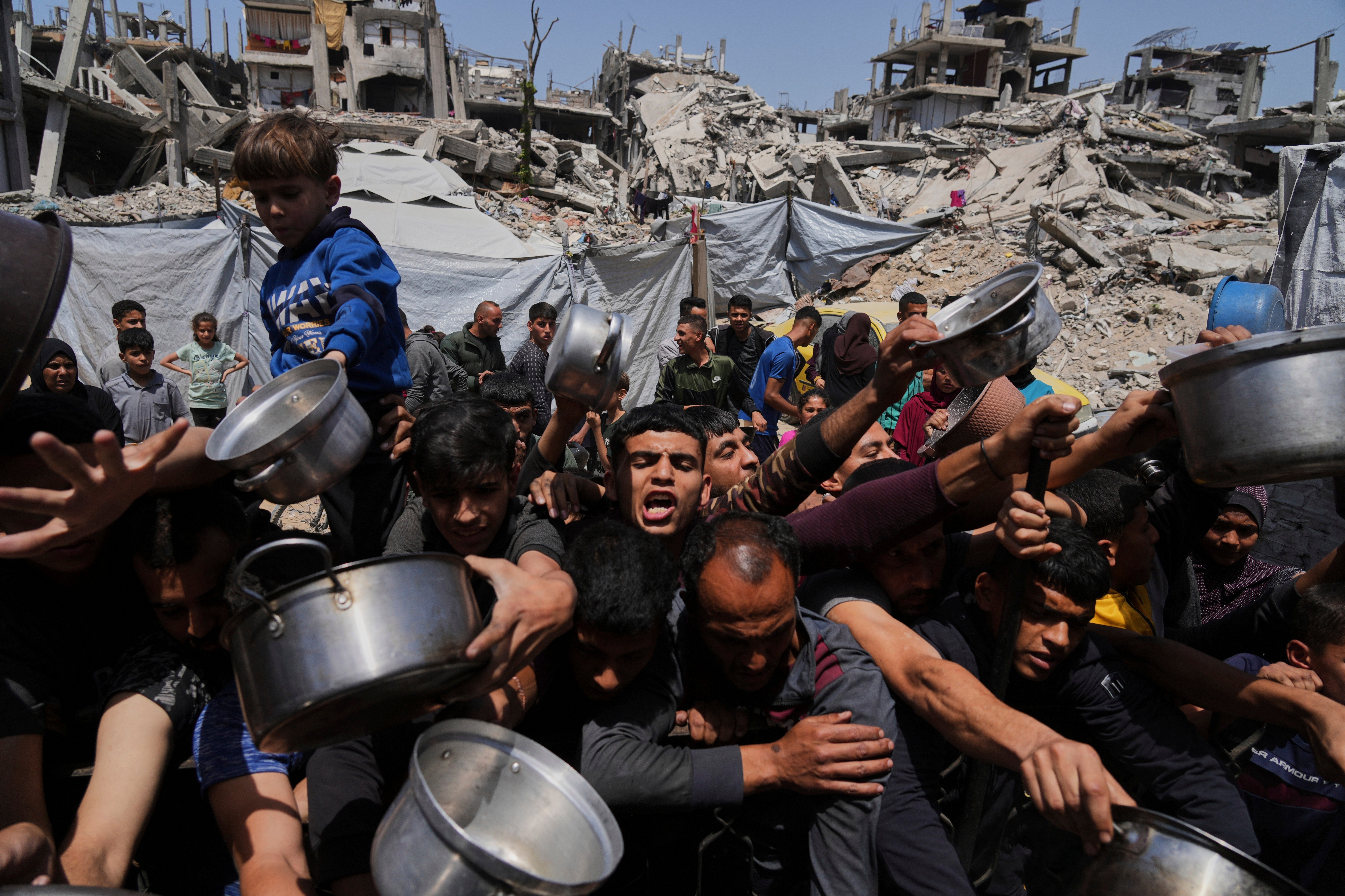 Palestinians struggle to get donated food at a community kitchen in Beit Lahia, northern Gaza Strip