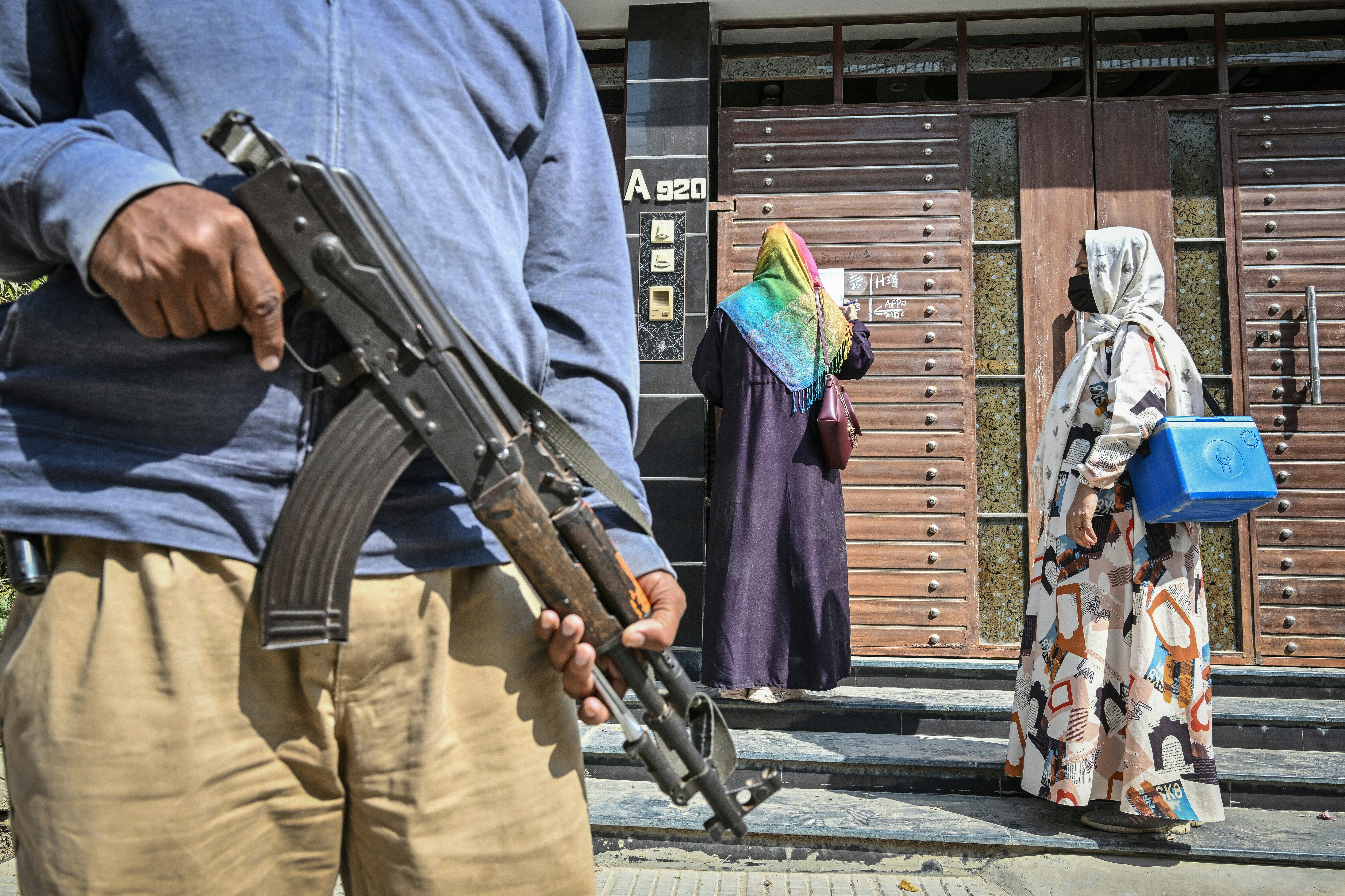 A policeman stands guard as health workers mark a house on the first day of a nationwide polio vaccination campaign in Karachi