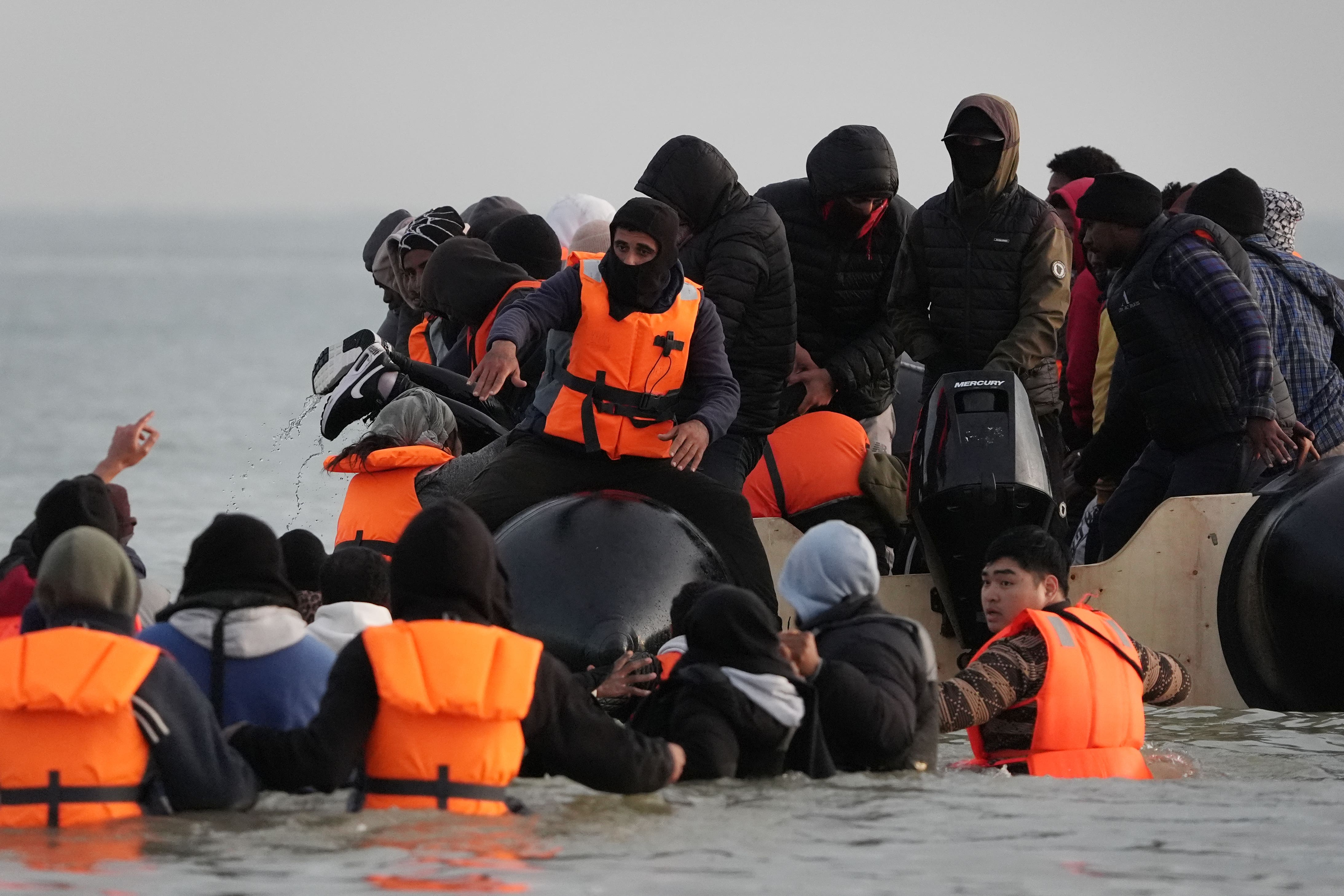 People thought to be migrants wade through the sea to board a small boat leaving the beach at Gravelines, France, on Saturday (Gareth Fuller/PA)