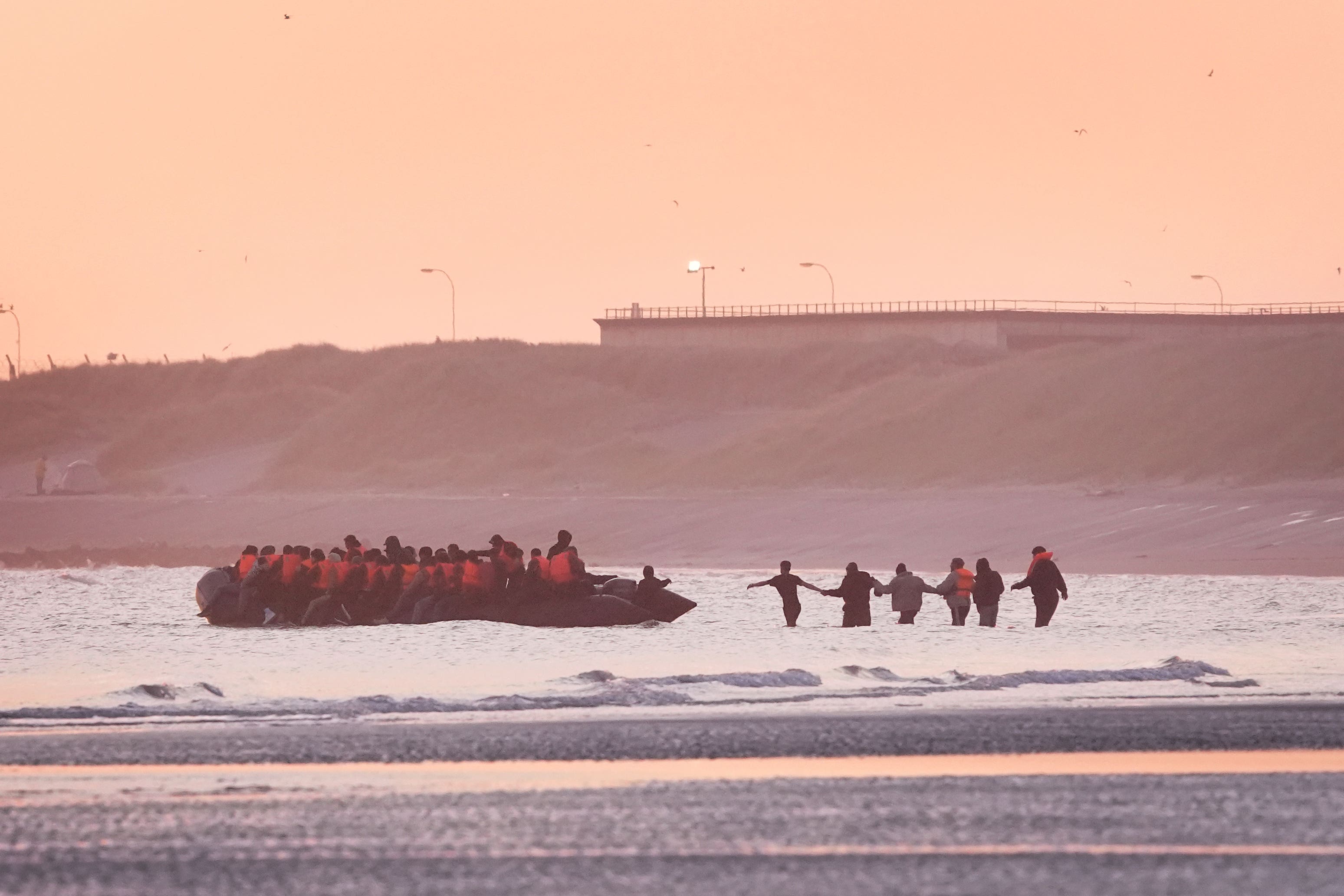 A group of people thought to be migrants wade into the sea to board an approaching small boat at Gravelines, France (Gareth Fuller/PA)