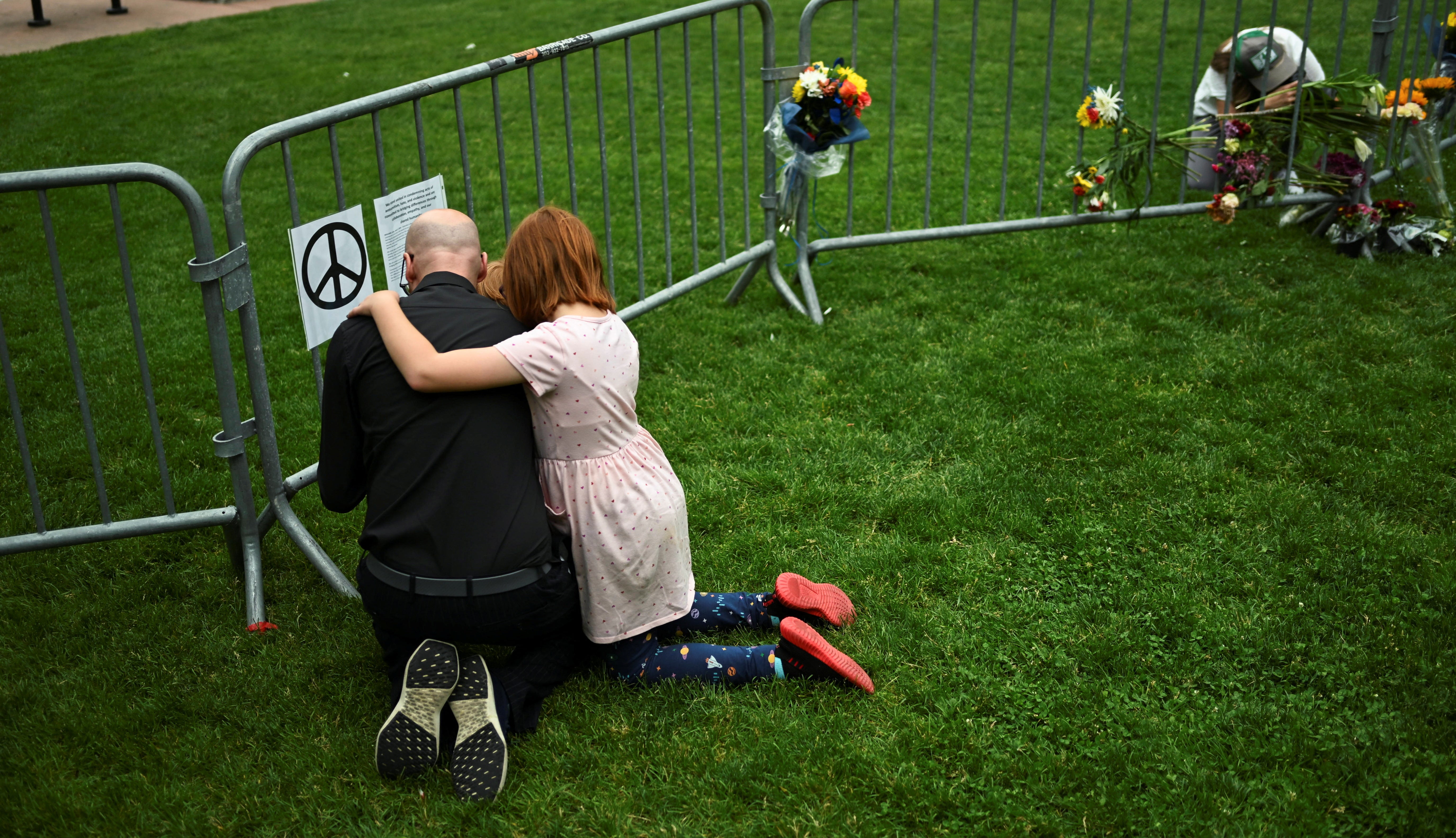 Jon Athan and his children embrace at a memorial at the scene of an attack that injured multiple people, outside the Boulder County Courthouse