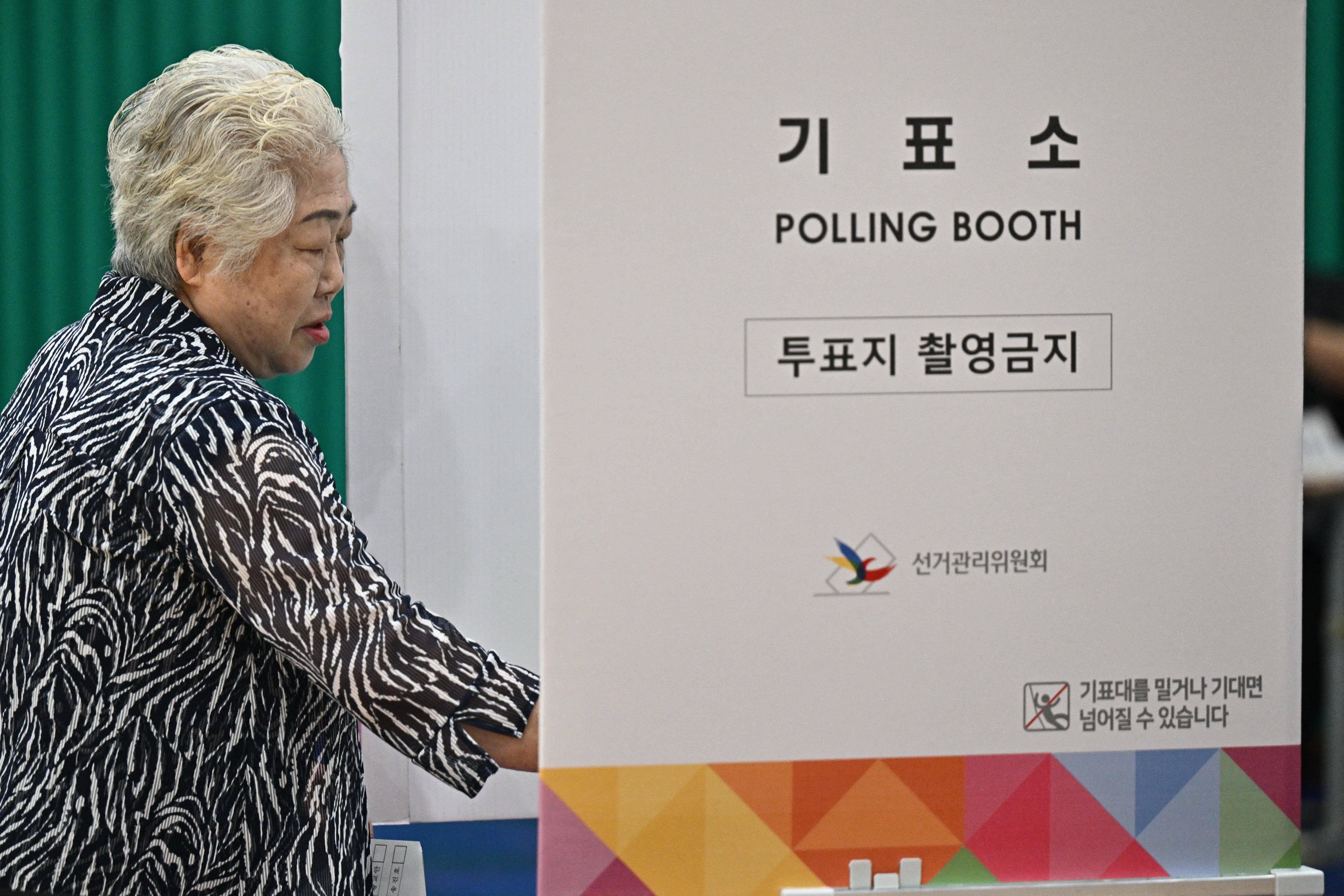 A woman enters a polling booth as she votes during the presidential election in Seoul on June 3, 2025