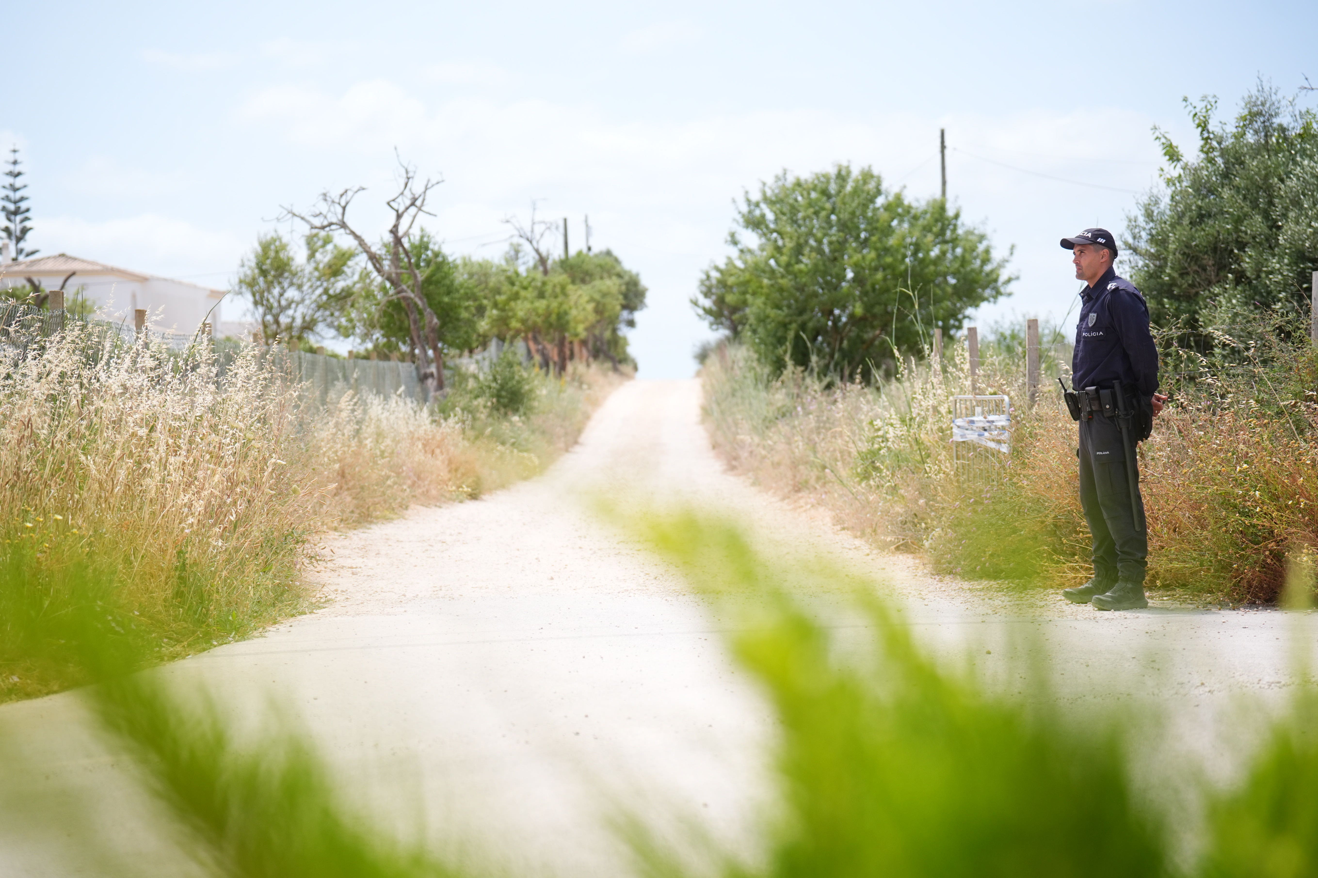 A Portuguese police officer patrols the entrance to a road to the west of Praia De Luz, Portugal, where searches are being carried out by officers investigating the disappearance of Madeleine McCann (James Manning/PA)