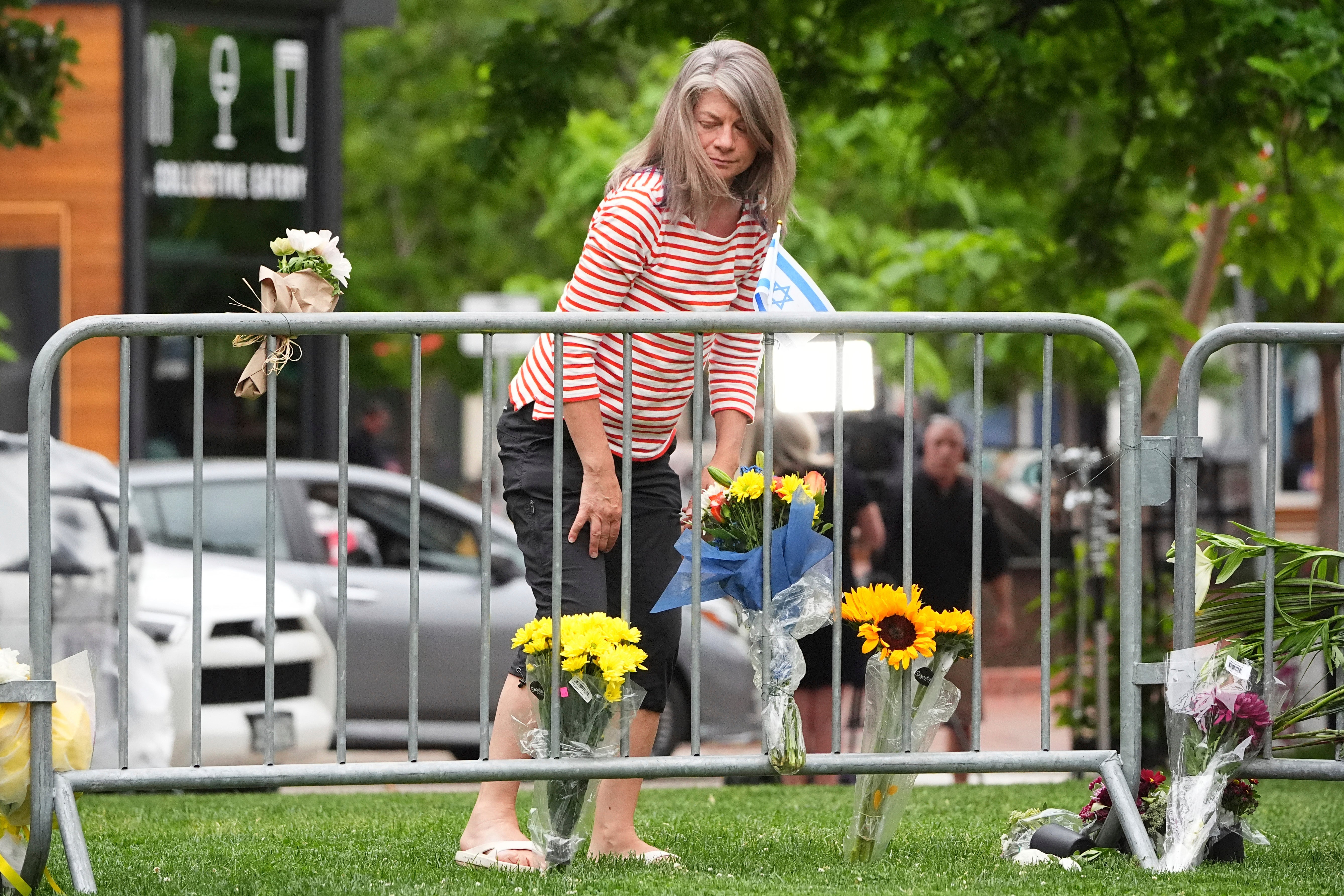 A woman places a bouquet of flowers at a makeshift memorial for victims of the flamethrower attack outside the Boulder County, Colo., courthouse.
