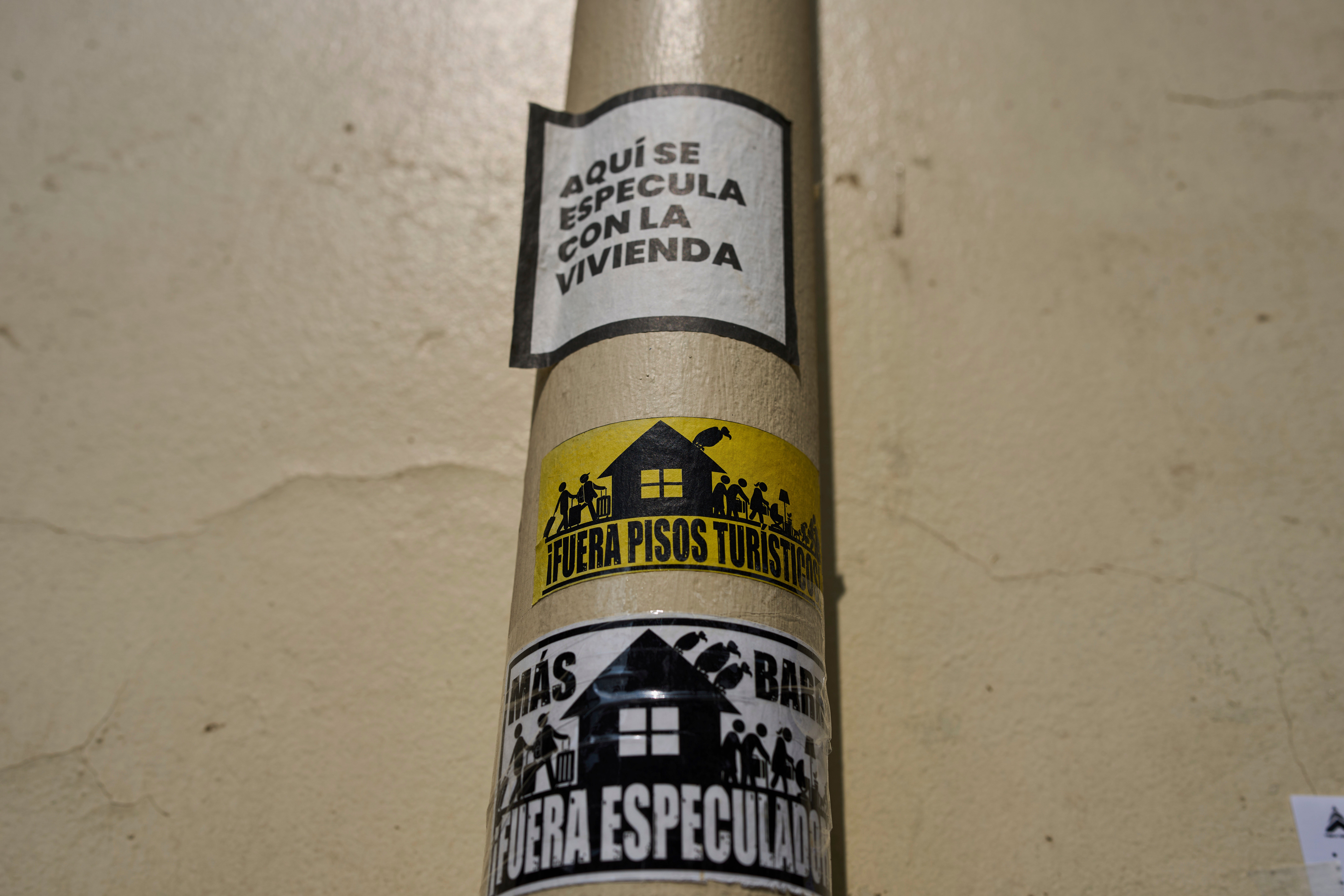 Stickers against tourist holiday rentals are attached on a pipe in downtown Madrid, Spain, Tuesday, June 3, 2025. The writing in Spanish reads: "This is a hotspot for housing speculation," "Tourist rentals out," and "More neighborhood, speculators out." (AP Photo/Manu Fernandez)