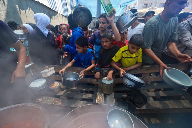 <p>Palestinians wait for food at a distribution point in Nuseirat, central Gaza Strip</p>