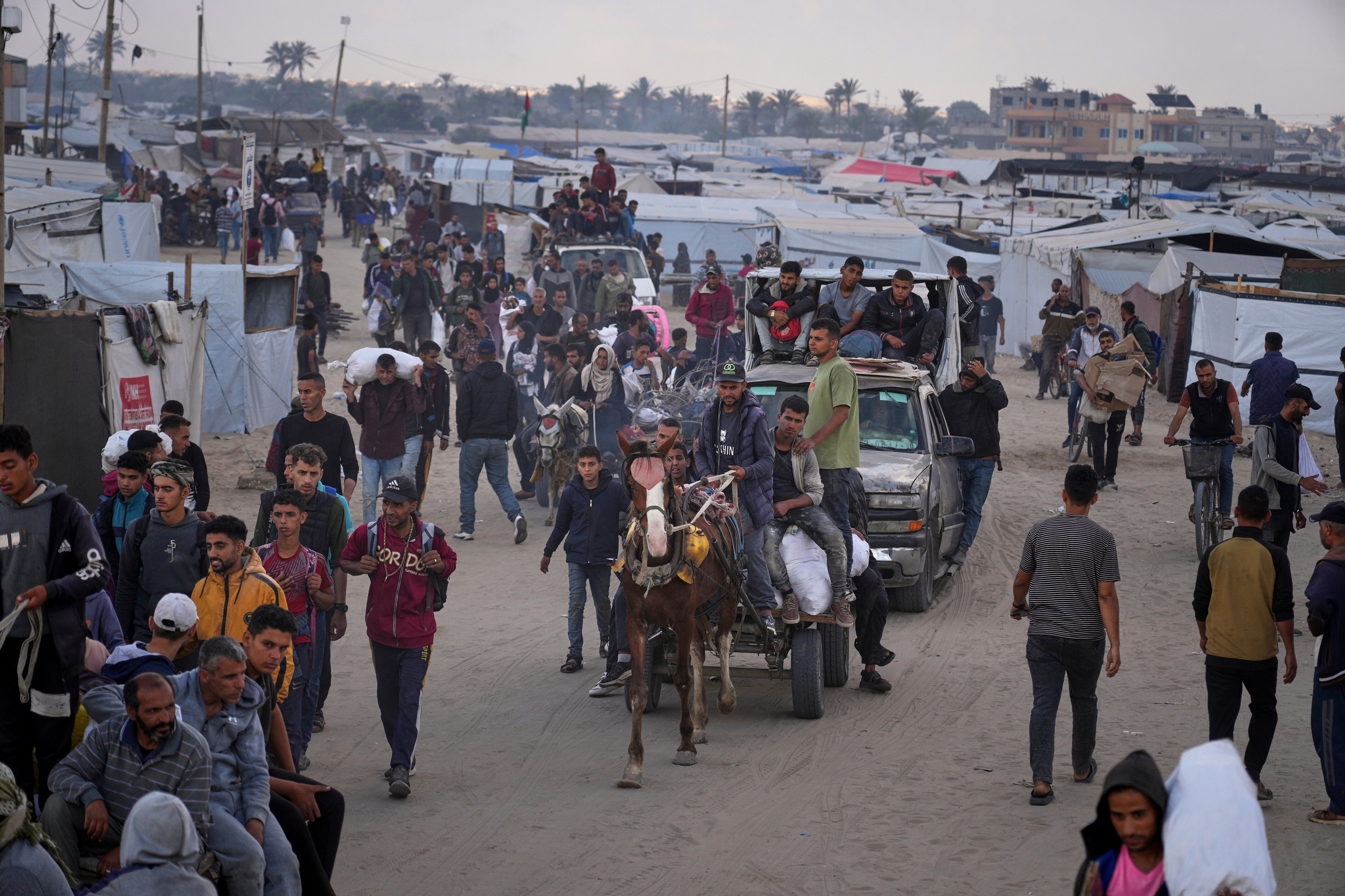 Palestinians carry bags filled with food and humanitarian aid provided by the Gaza Humanitarian Foundation