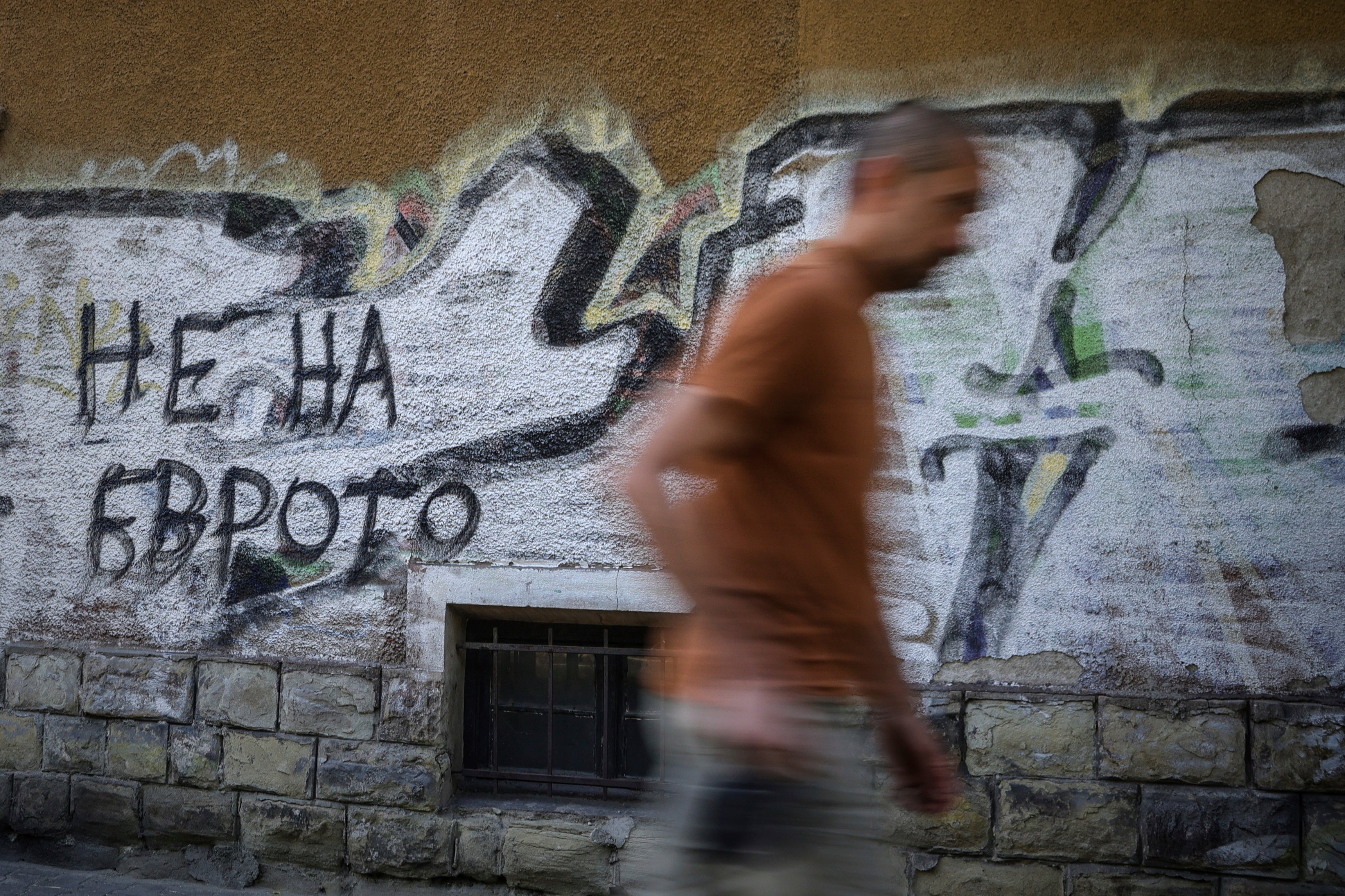 A man passes by graffiti reading 'No to Euro'