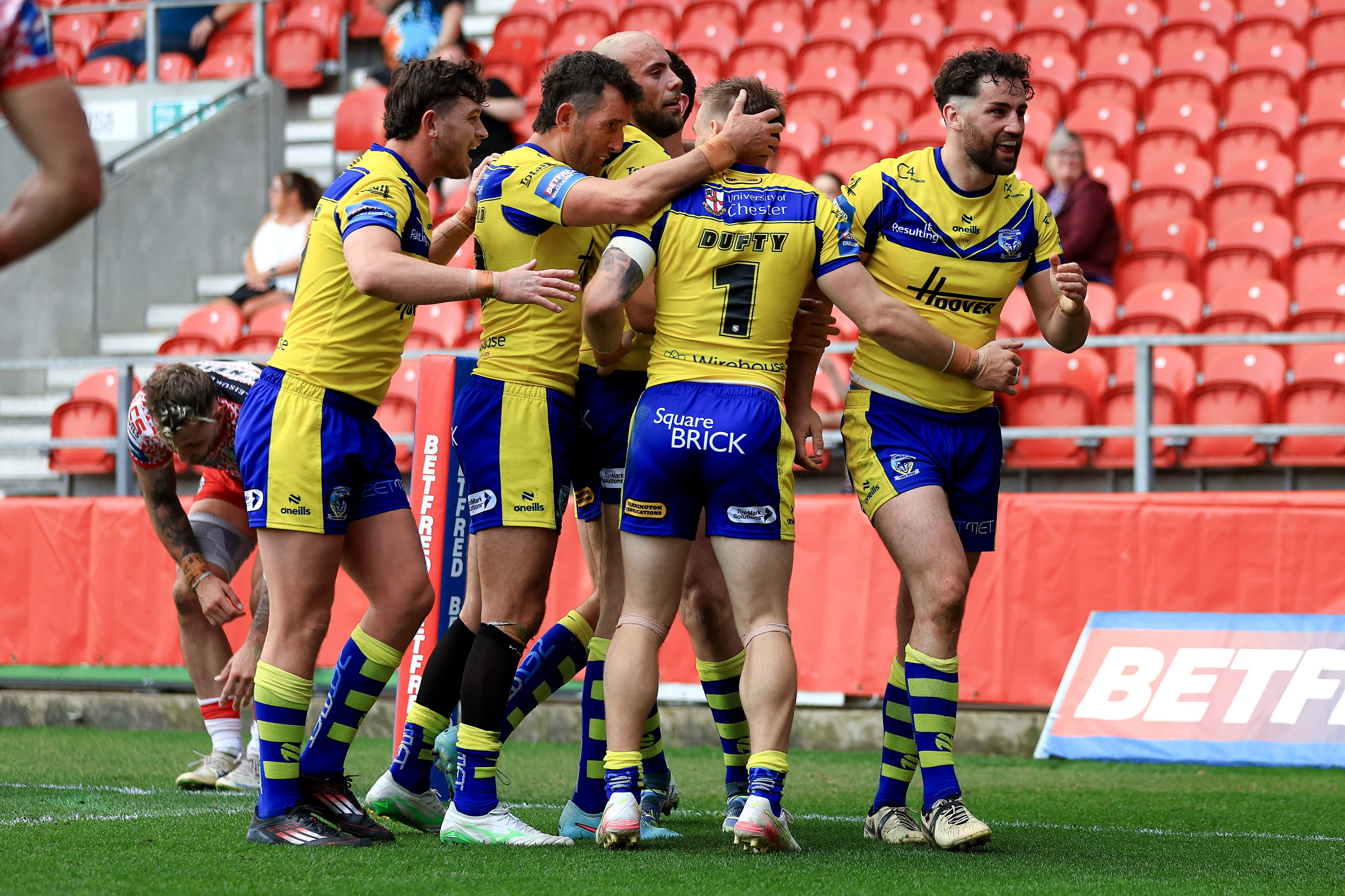 Toby King of Warrington Wolves, right, celebrates with teammates after scoring his team's third try against Leigh Leopards on May 11