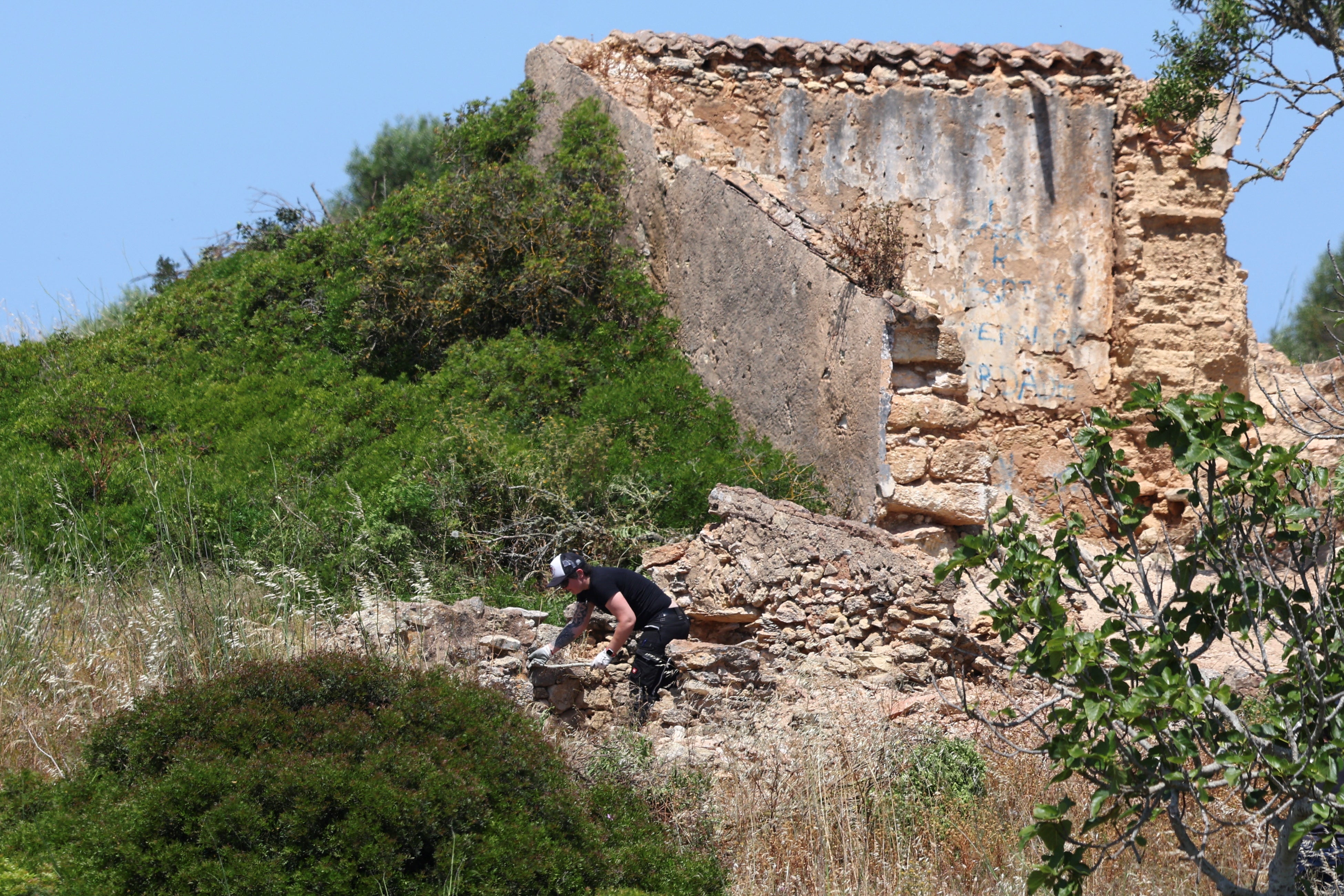 A criminal police investigator searches the area near a ruin as police resumes the search for the body of Madeleine McCann, who went missing in the Portuguese Algarve in May 2007, in Atalaia, Portugal, June 5, 2025. REUTERS/Pedro Nunes