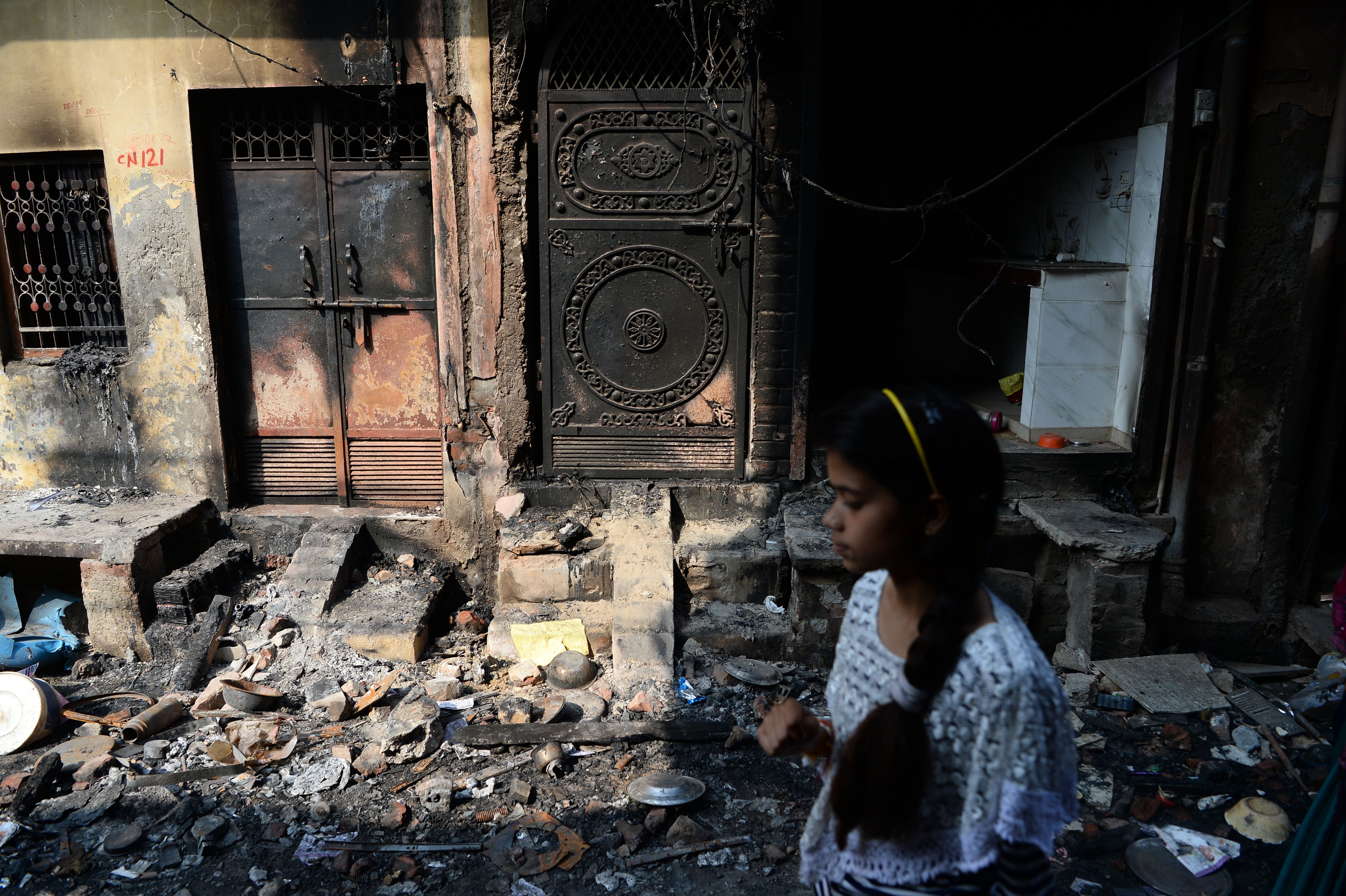 A resident walks past a destroyed residential building following sectarian riots in New Delhi in 2020