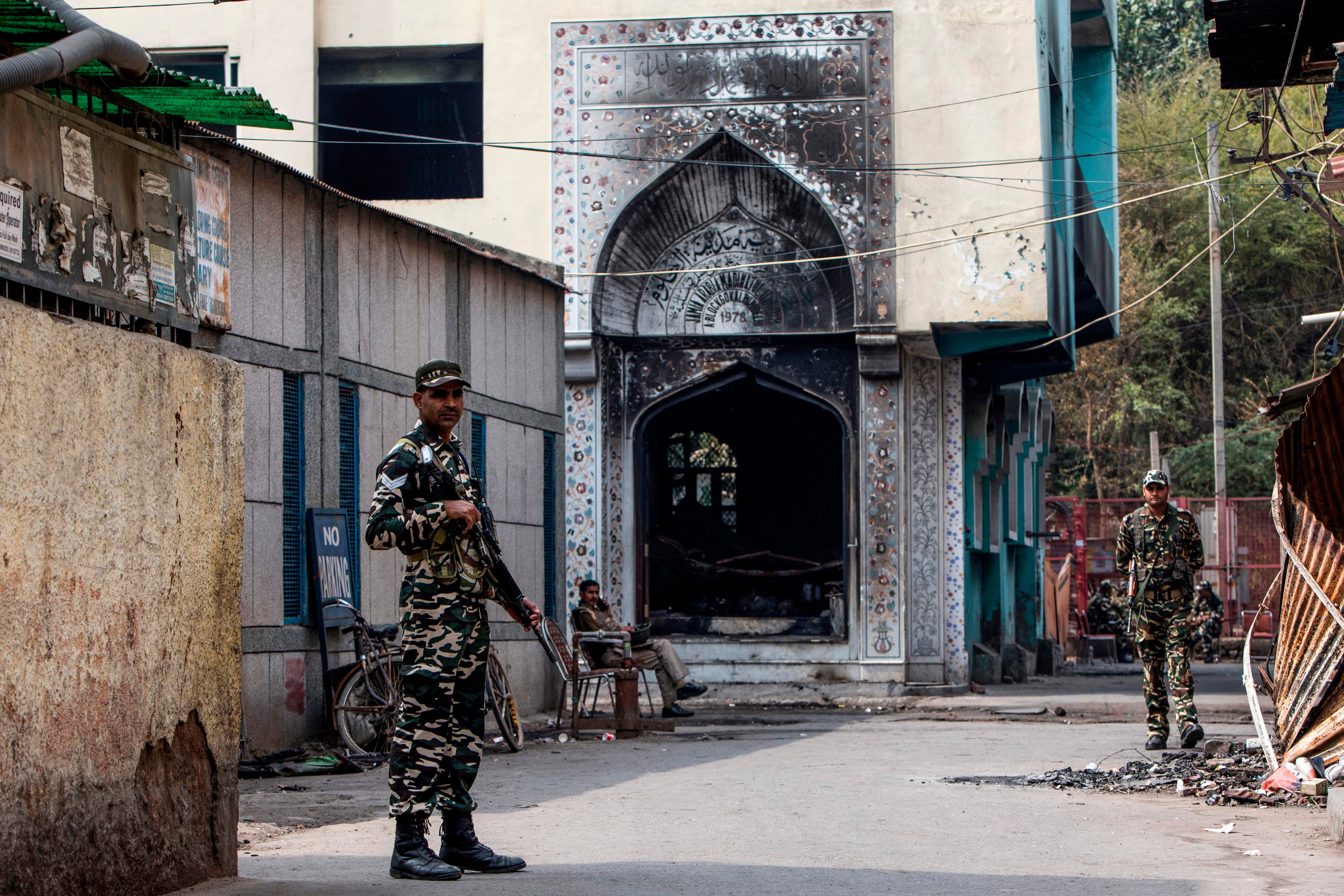 Security personnel stand guard outside a mosque burnt by a Hindu mob during sectarian riots in Delhi on 28 February 2020