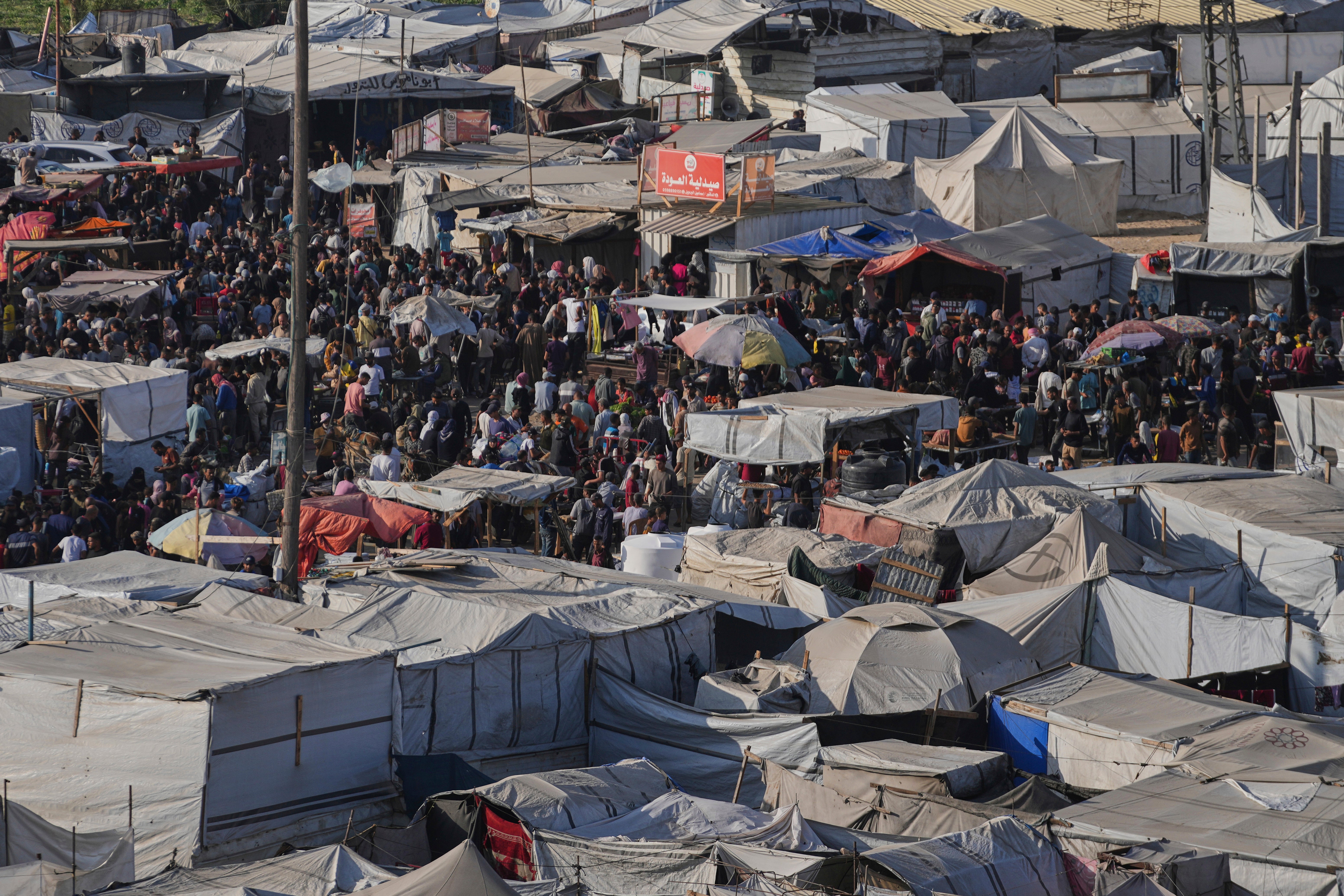 Displaced Palestinians walk trough a makeshift tent camp in Khan Younis, Gaza