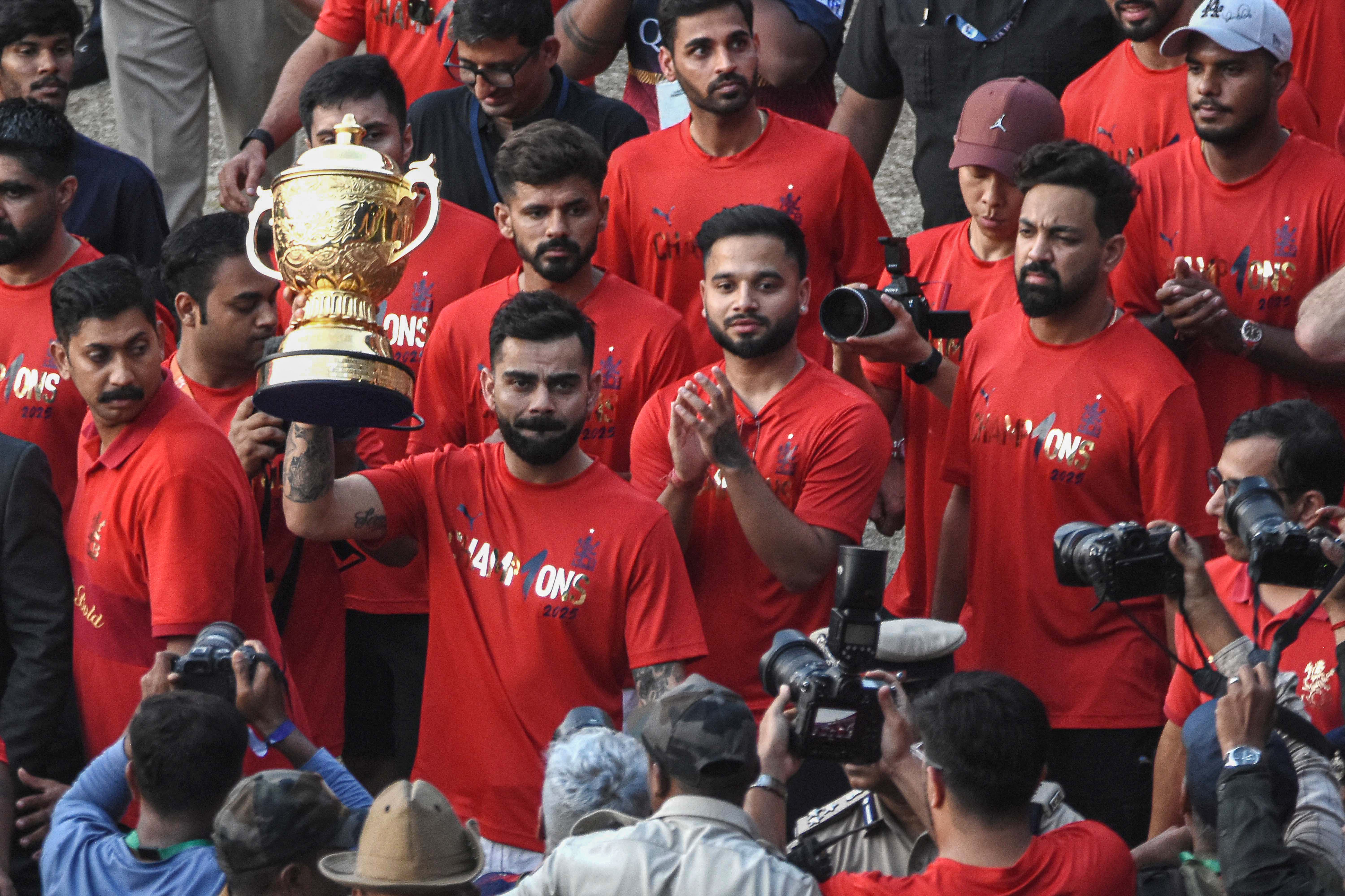 Royal Challengers Bengaluru's Virat Kohli (2L) holds the Indian Premier League trophy aloft alongside teammates outside the M. Chinnaswamy Stadium as they celebrate with fans winning the Indian Premier League (IPL) title