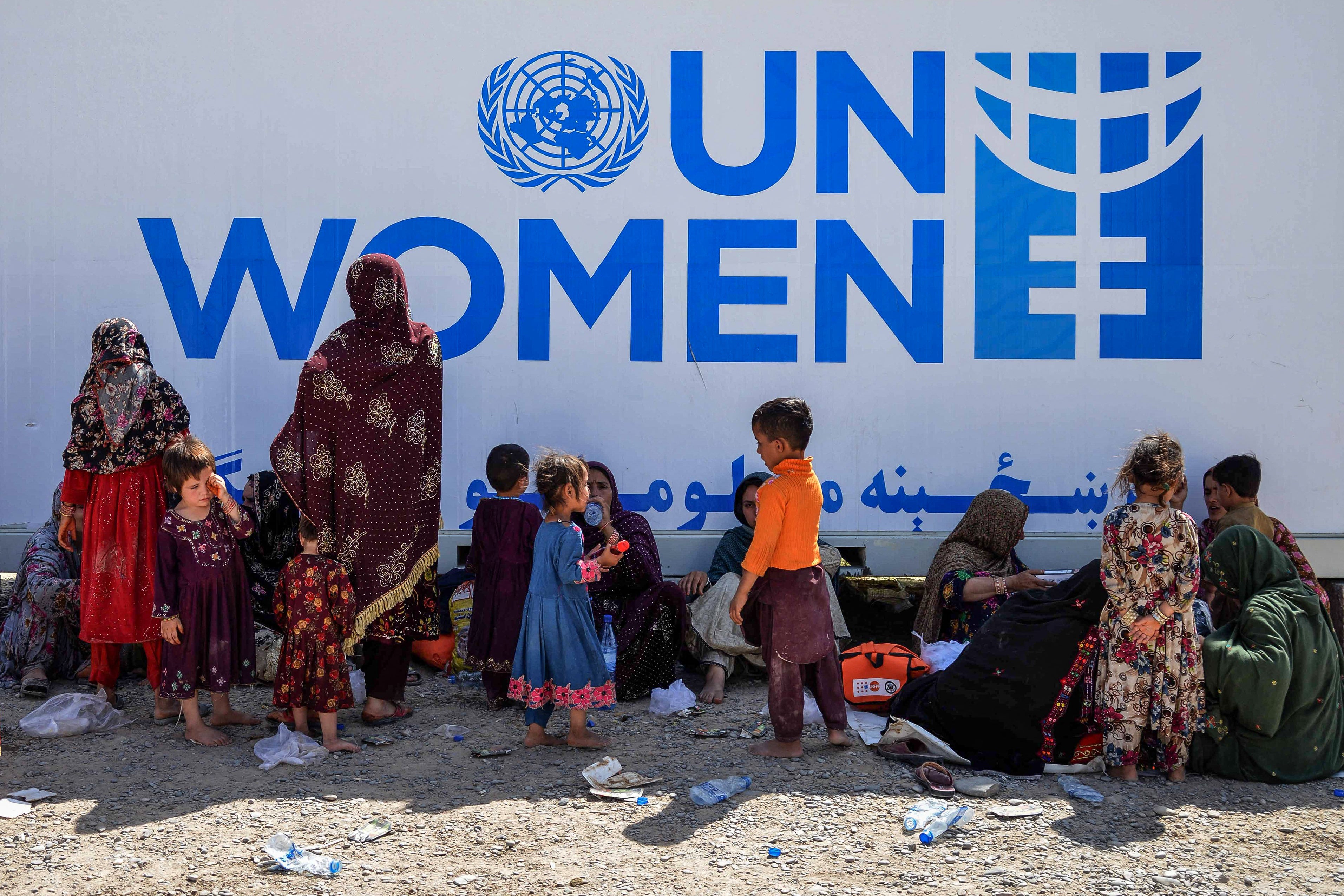 Afghan refugee women and children rest near a UN information office for women in Afghanistan’s Kandahar