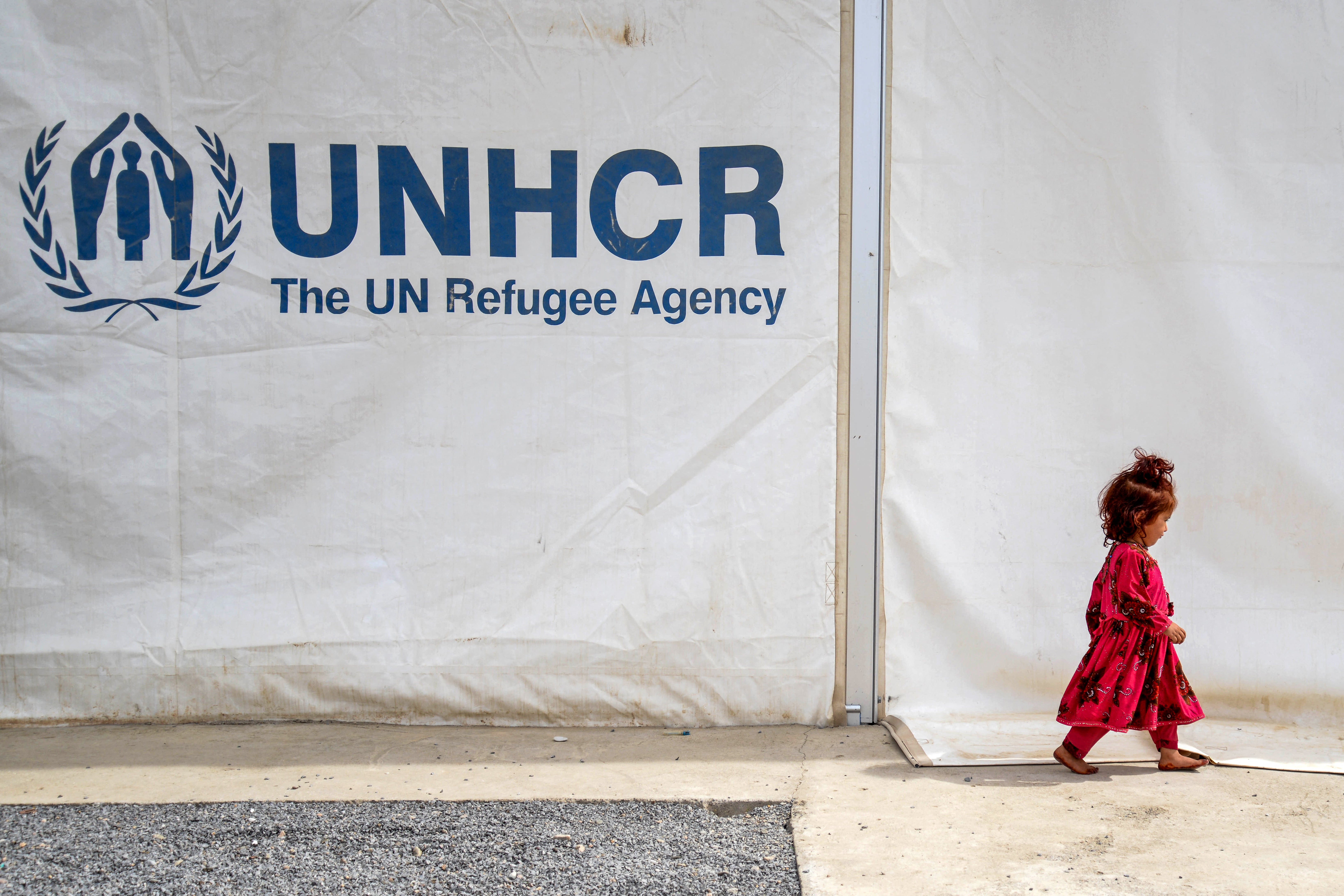An Afghan refugee girl walks past a registration centre with the United Nations High Commissioner for Refugees